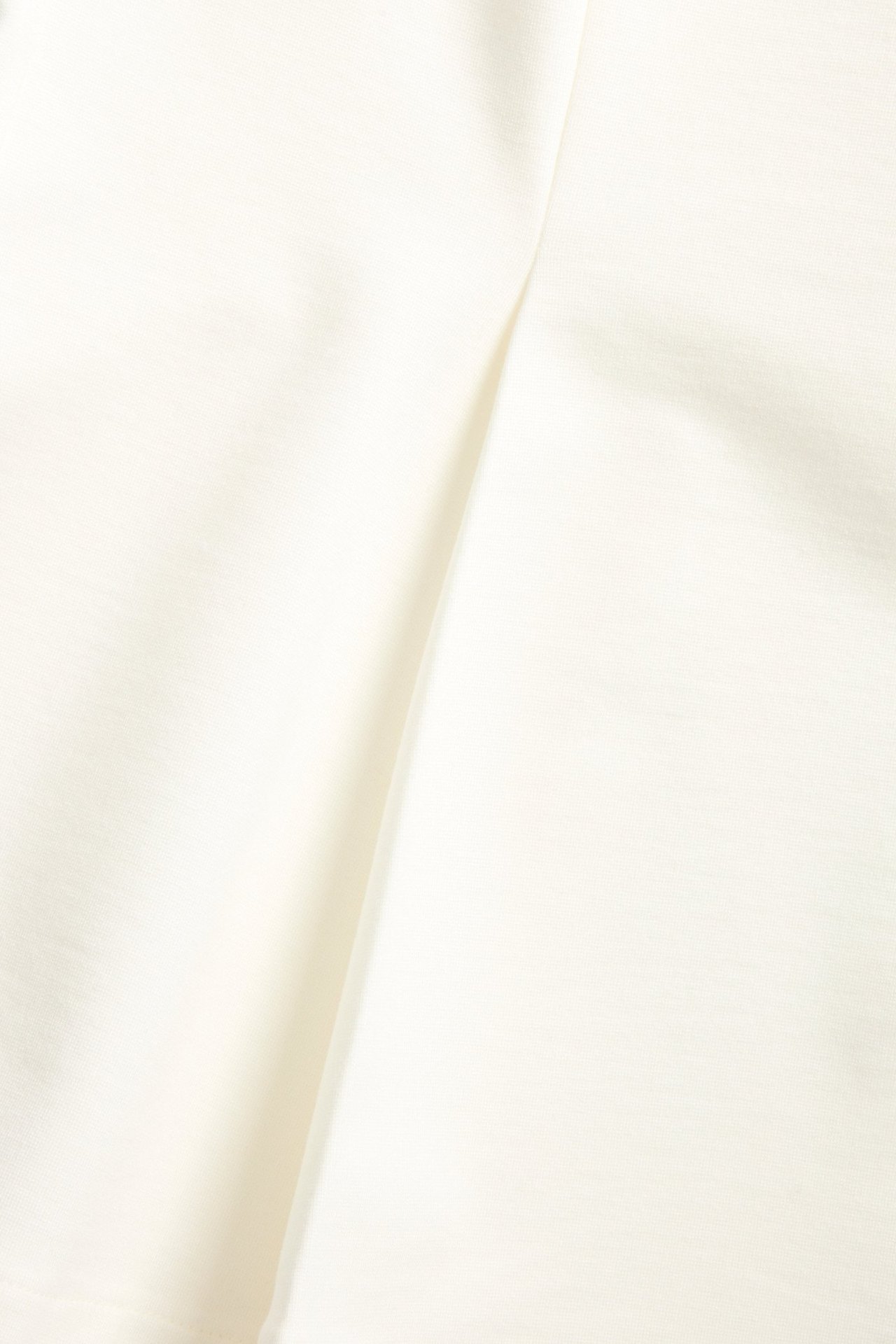 Zbliżenie na gładką, jednolitą tkaninę punto w kolorze off-white z topu peplum.