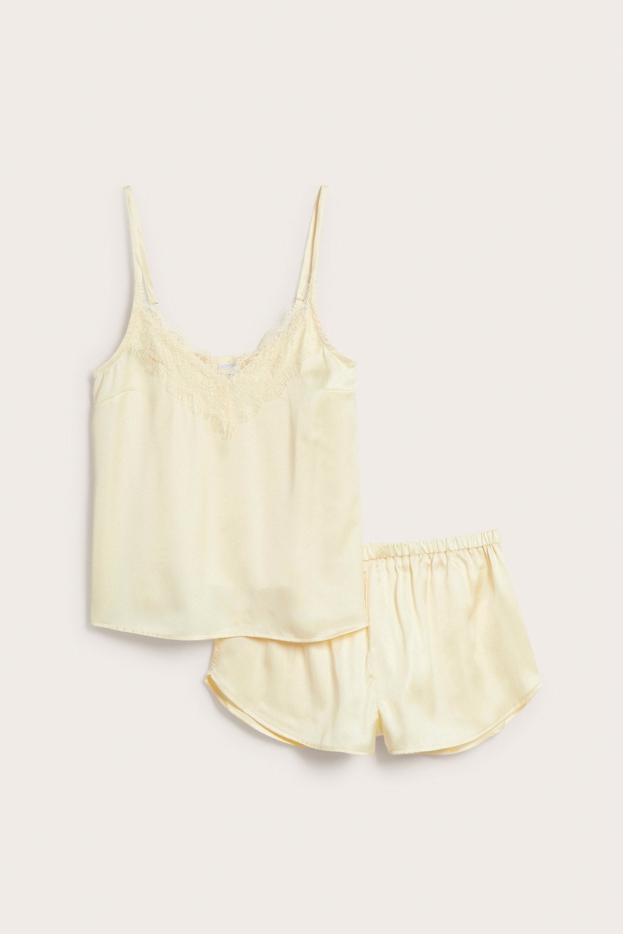 Framifrån: Ljusgul pyjamas i satin med spetsdetaljer på linnet och matchande shorts med resår i midjan.