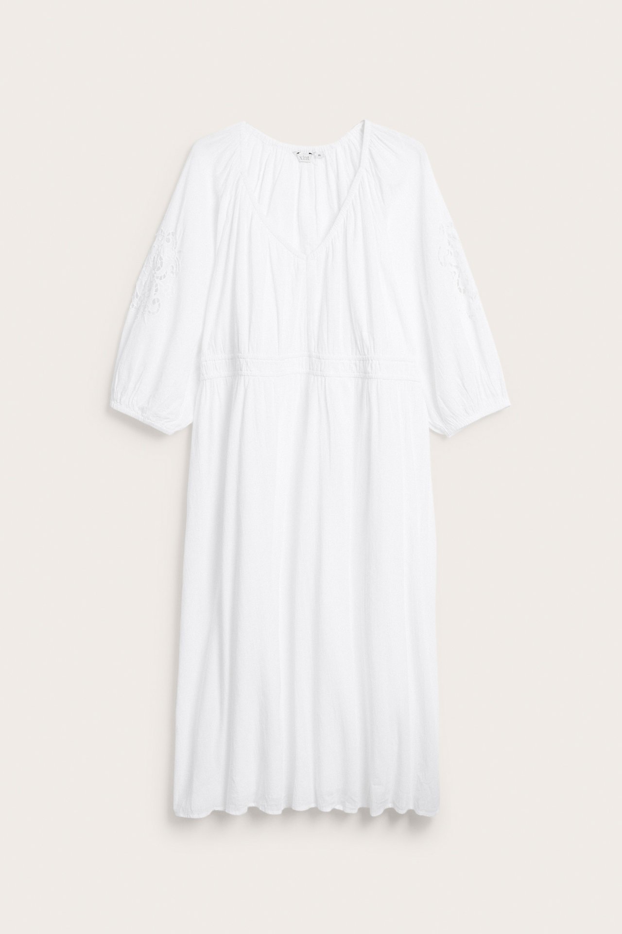 Valkoinen pitkä puuvillamekko, jossa V-pääntie, joustava vyötärö ja kirjaillut hihat, edestä.