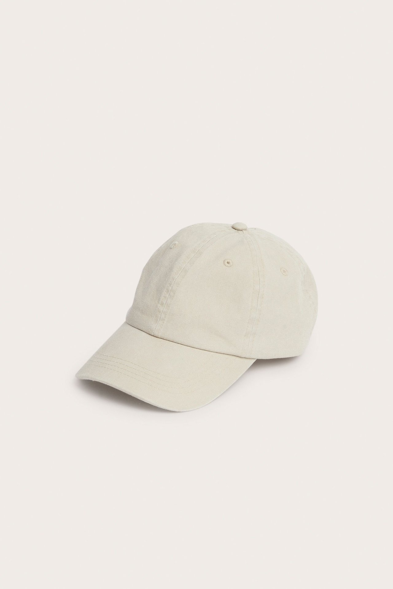 Forsidevisning av en lys beige ensfarget caps i vasket bomullstwill.