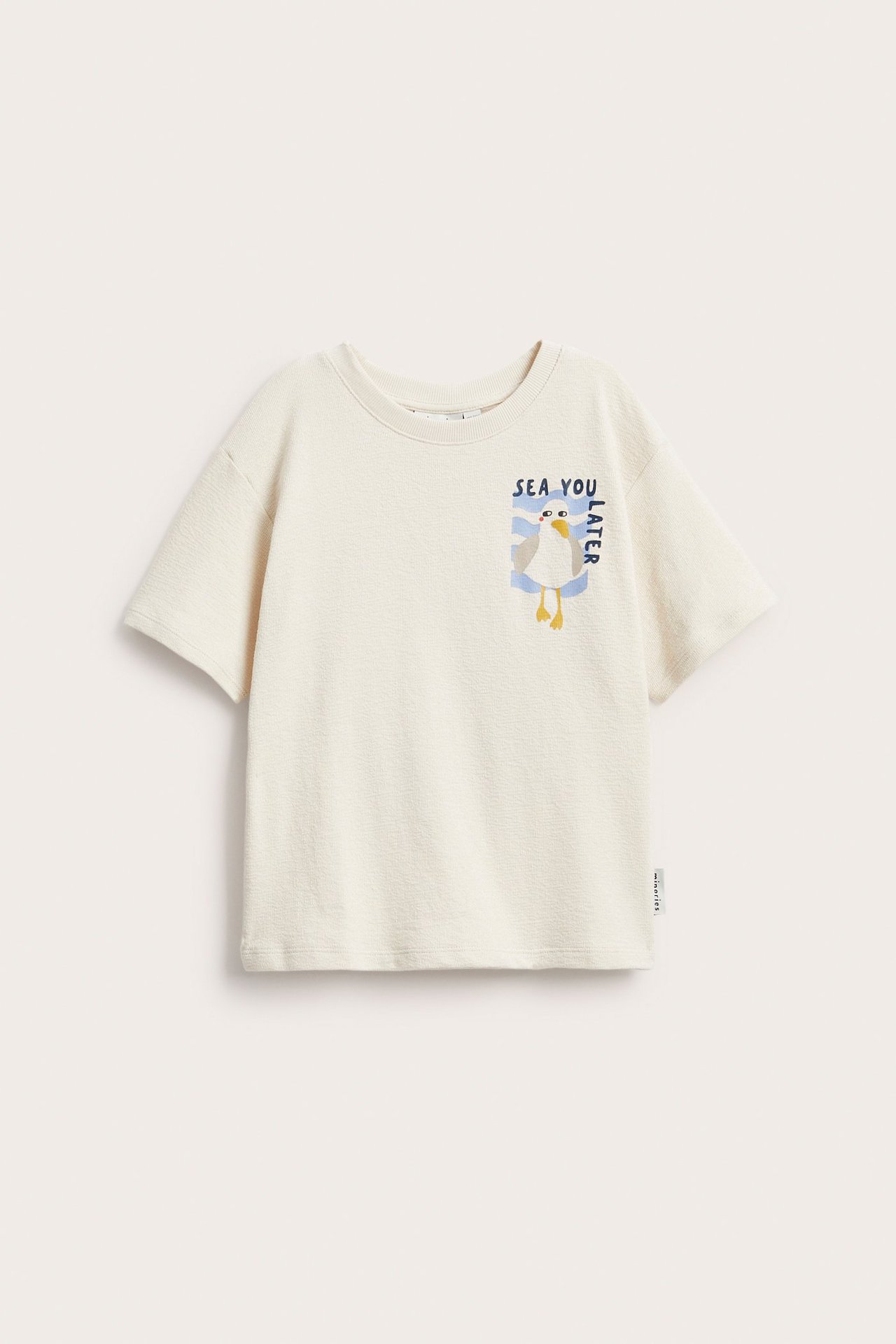 Frontvy av en ljusbeige bomulls-t-shirt för barn med sjöfågelstryck och texten 'SEA YOU LATER'.
