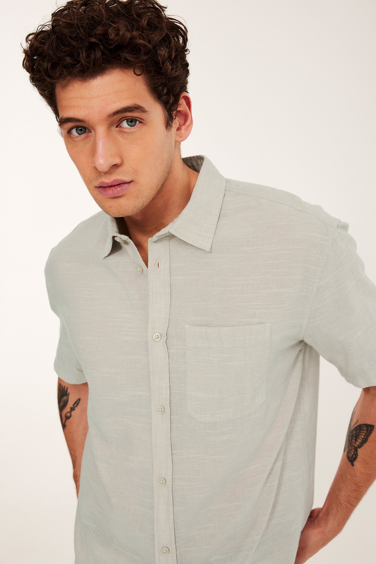 Edestä näkymä miehestä, yllään vaaleanbeige lyhythihainen regular fit paita rakenteellisella kuviolla ja rintataskulla.