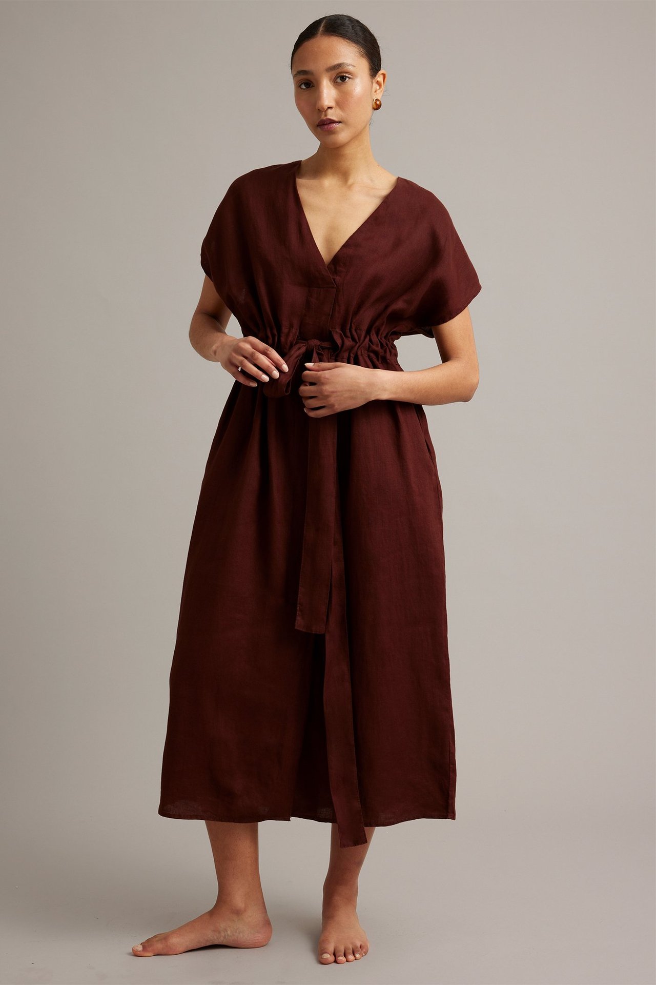 Frontbilde: kvinne i vinrød lin midikjole med V-hals og knytebelte i midjen.