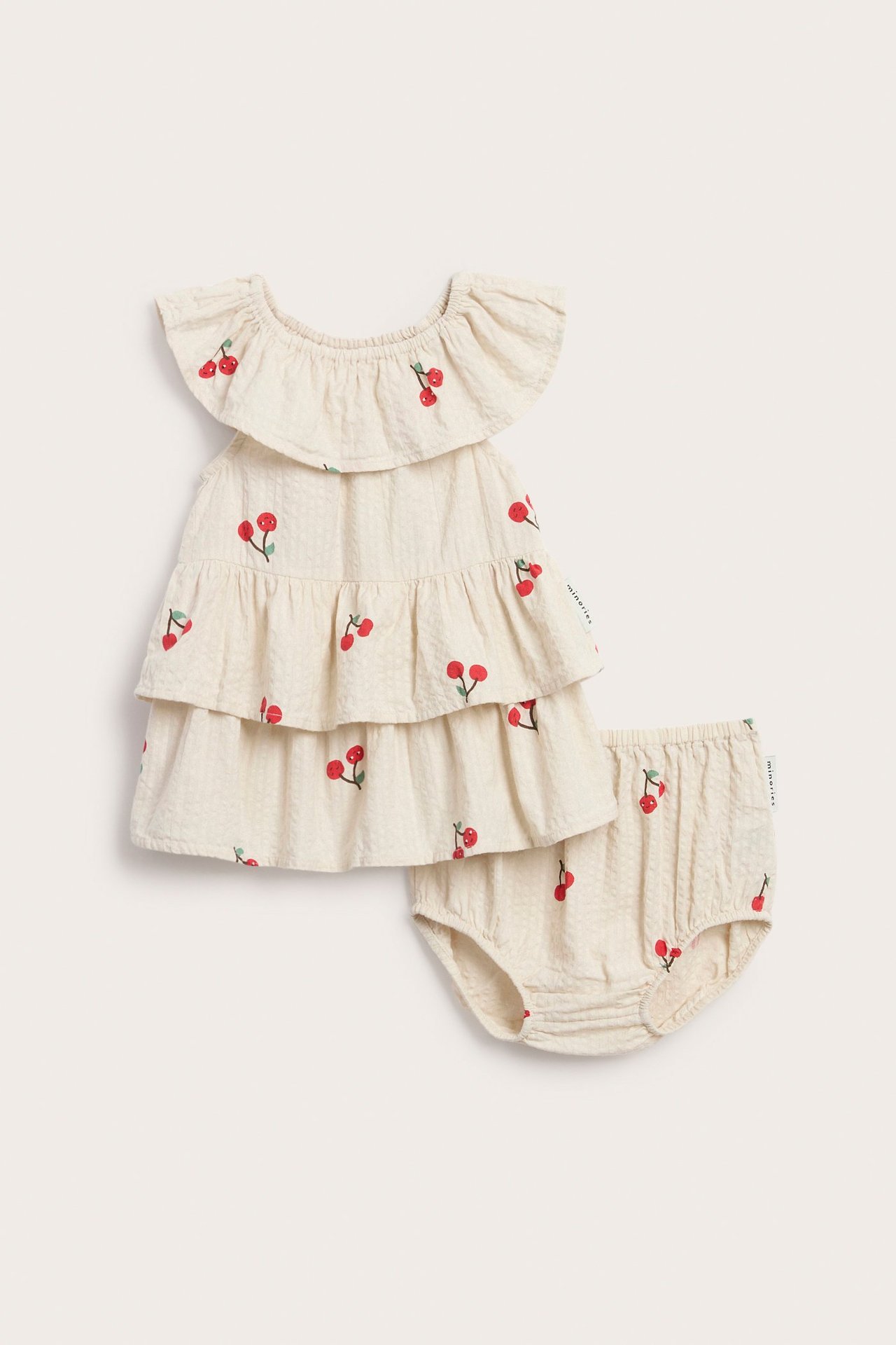 Edestä: vauvan beige seersucker-mekko kirsikkakuviolla ja yhteensopivat bloomers-housut.