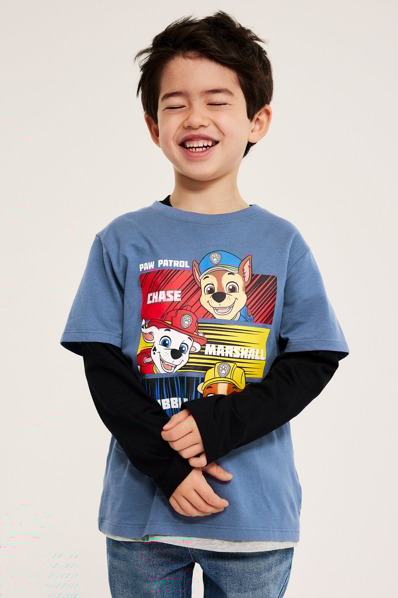 Dziecięcy niebieski T-shirt z nadrukiem Psiego Patrolu, na czarnej koszulce, z dżinsami. Widok z przodu.
