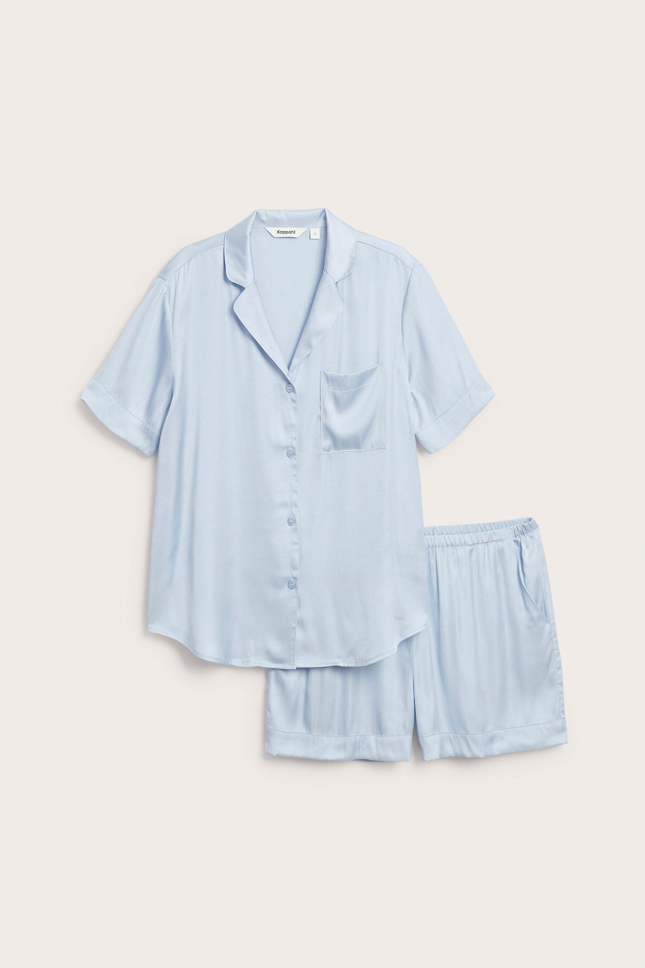Forfra, lys blå viskose-satin pyjamas: kortermet topp med brystlomme og matchende shorts med lommer.