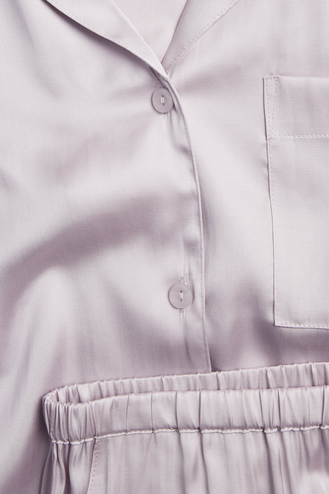 Närbild framifrån på ljuslila pyjamastopp i viskos med knappar, bröstficka och matchande shorts med resår.