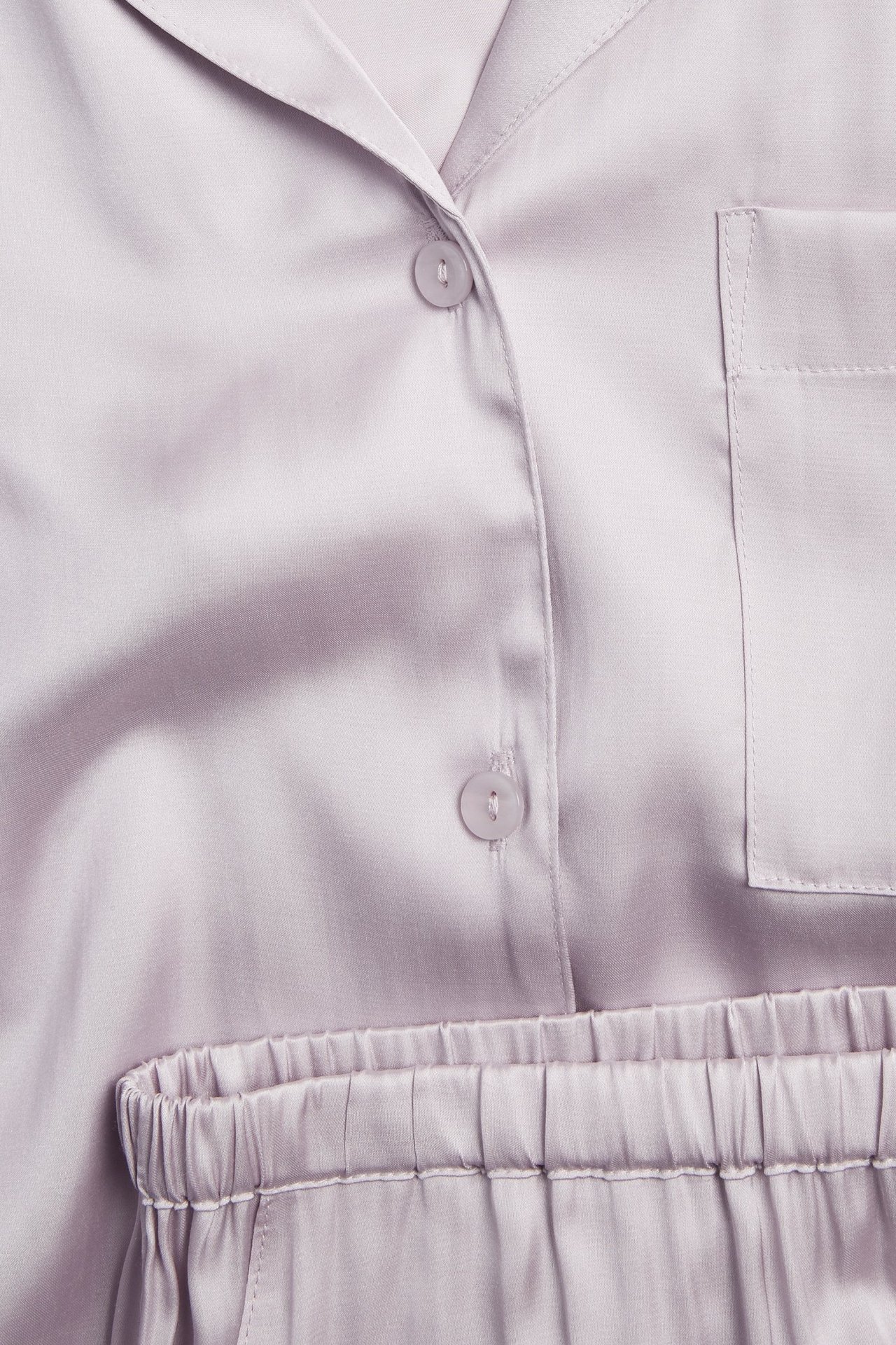 Lähikuva edestä: vaaleanlila viskoosipyjamanpaita napeilla, rintataskulla ja joustavilla shortseilla.