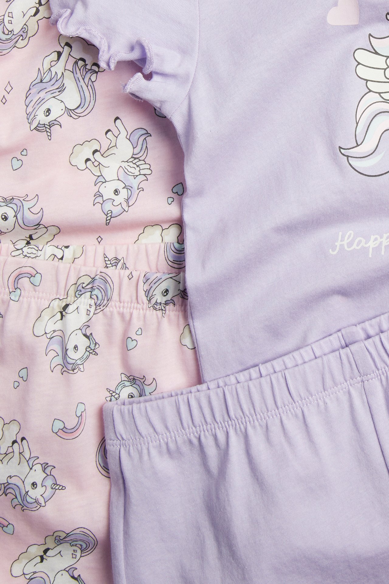 Zbliżenie na dwie dziecięce bawełniane piżamy: jasnofioletowy komplet z grafiką jednorożca i różowy komplet w jednorożce.