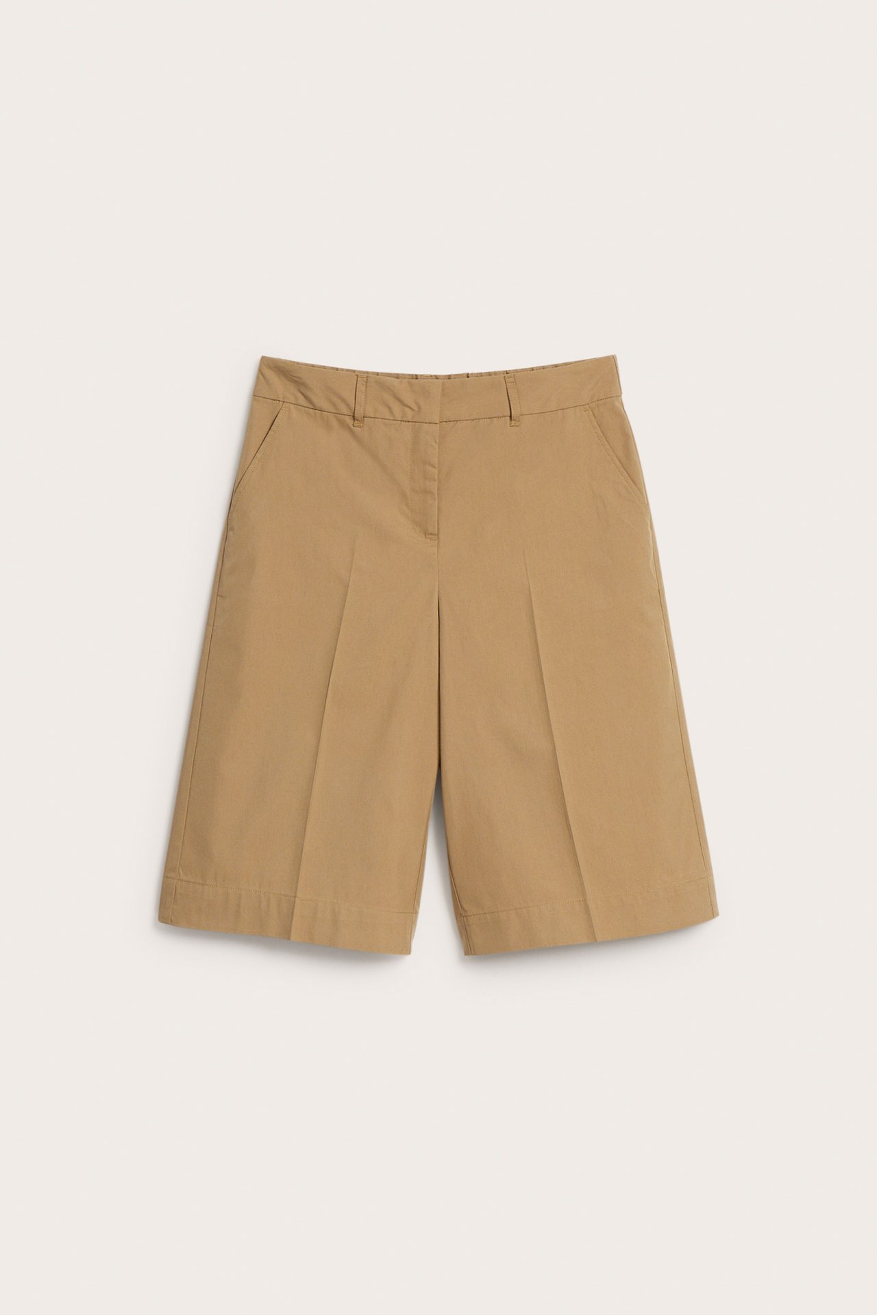 Frontvy av ensfargede beige bomullsblanding bermudashorts med beltehemper og sidelommer.