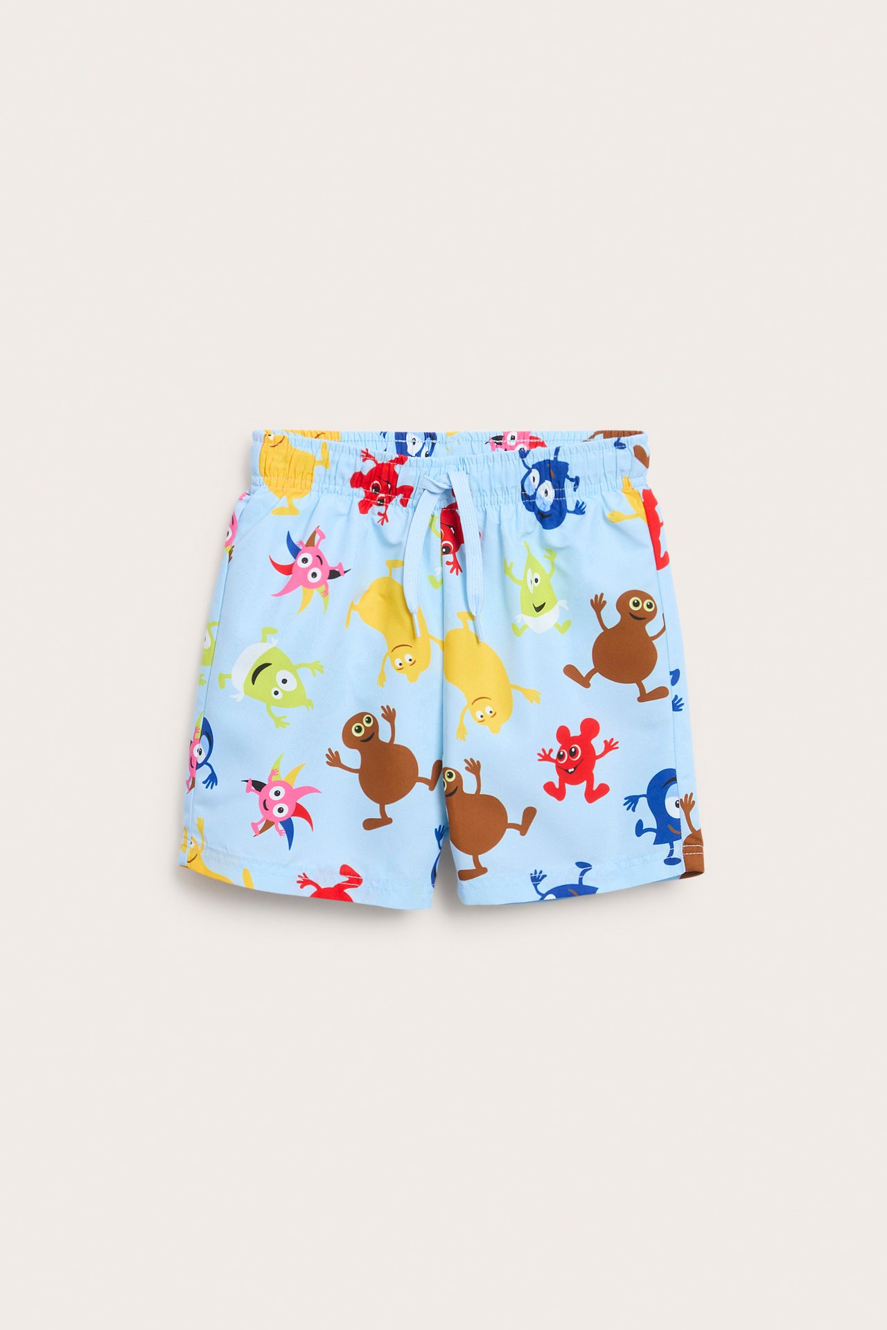 Lyseblå badeshorts for barn med Babblarna-mønster og hvit snøring i midjen, sett forfra.