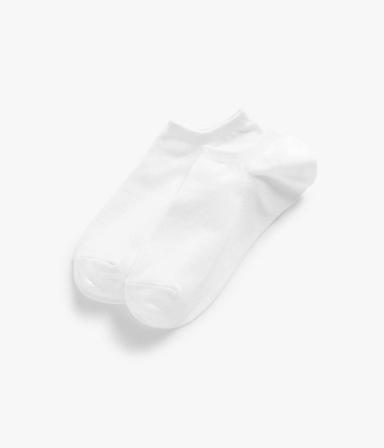 Widok z góry na dwie białe bawełniane skarpetki stopki, jedna lekko zachodzi na drugą.