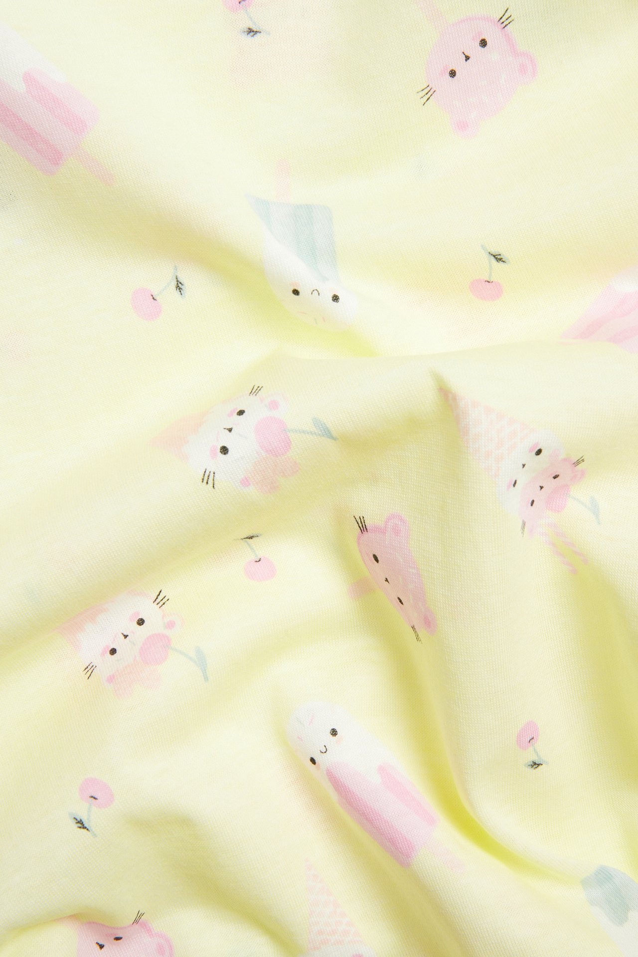 Zbliżenie na jasnożółtą bawełnianą koszulę nocną dziecięcą ze wzorem lodów.