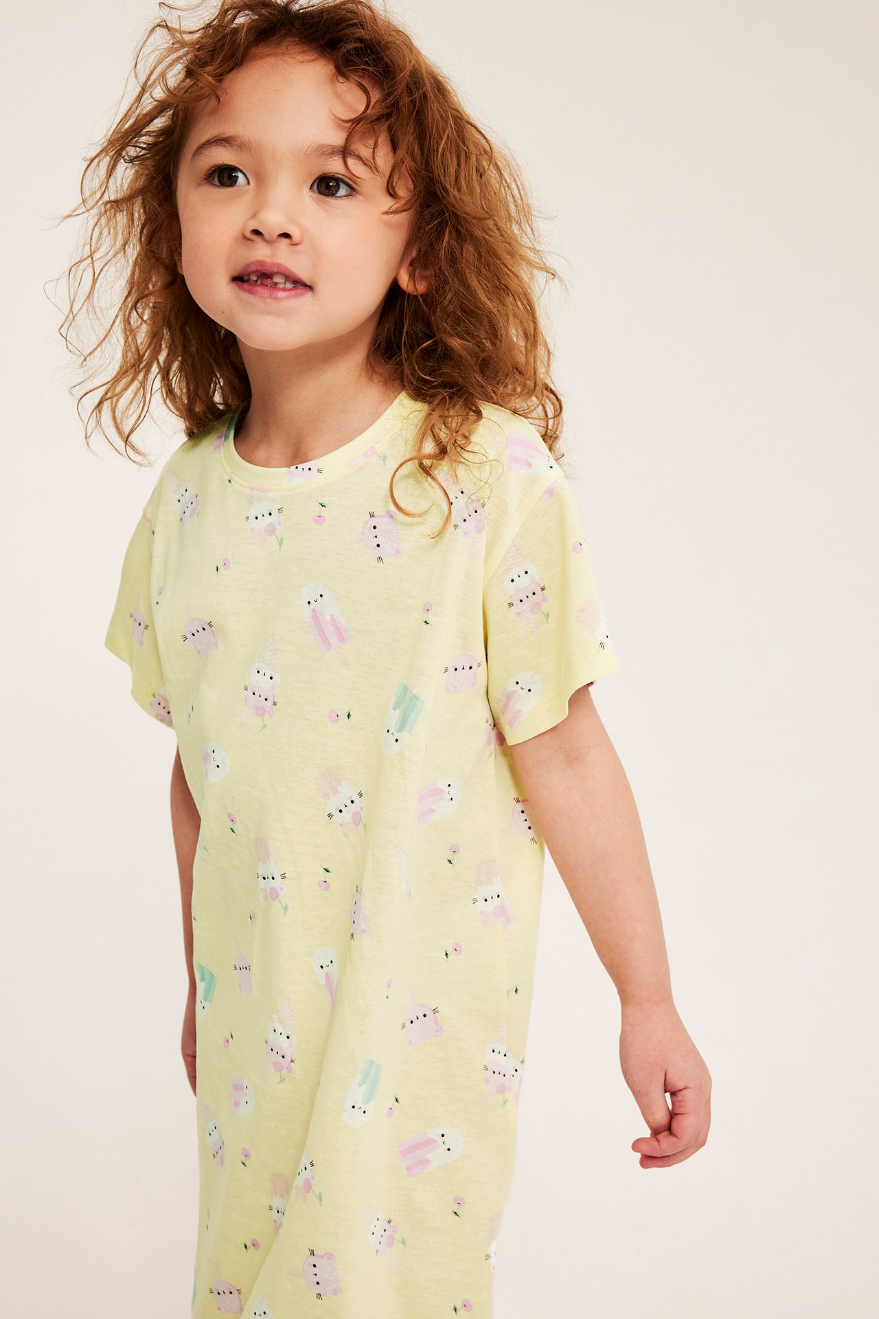 Edestä, lapsi pukeutuneena vaaleankeltaiseen lyhythihaiseen puuvillaiseen yömekkoon jäätelökuviolla.