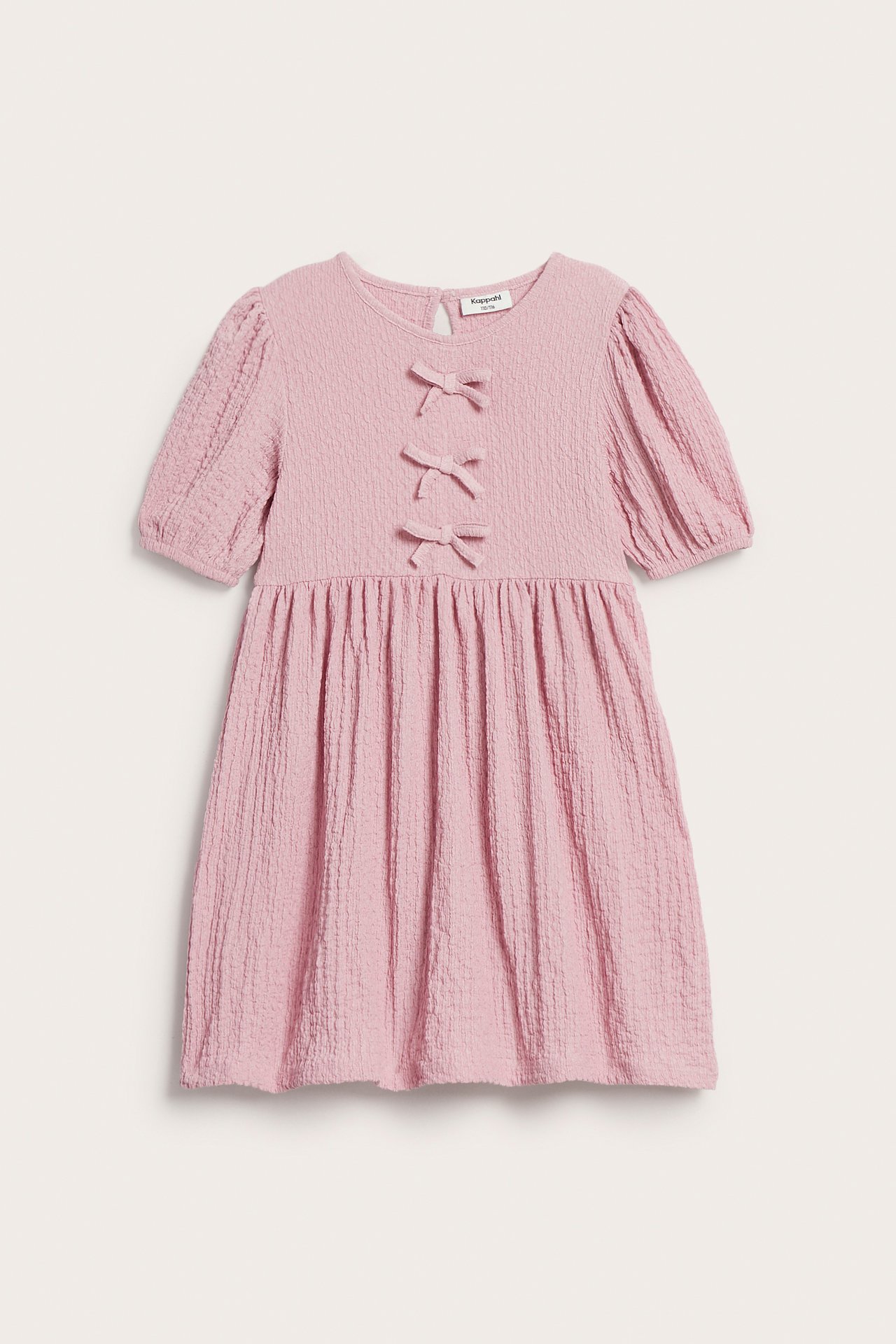 Frontbilde av en lys rosa krøllete jerseykjole for barn med puffermer og tre sløyfer.