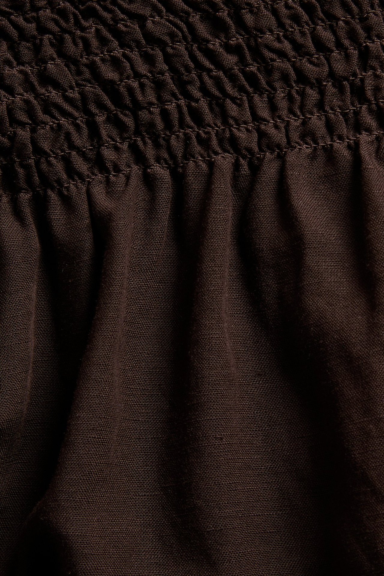 Nærbilde av mørkebrune linblanding shorts med smock-midje.