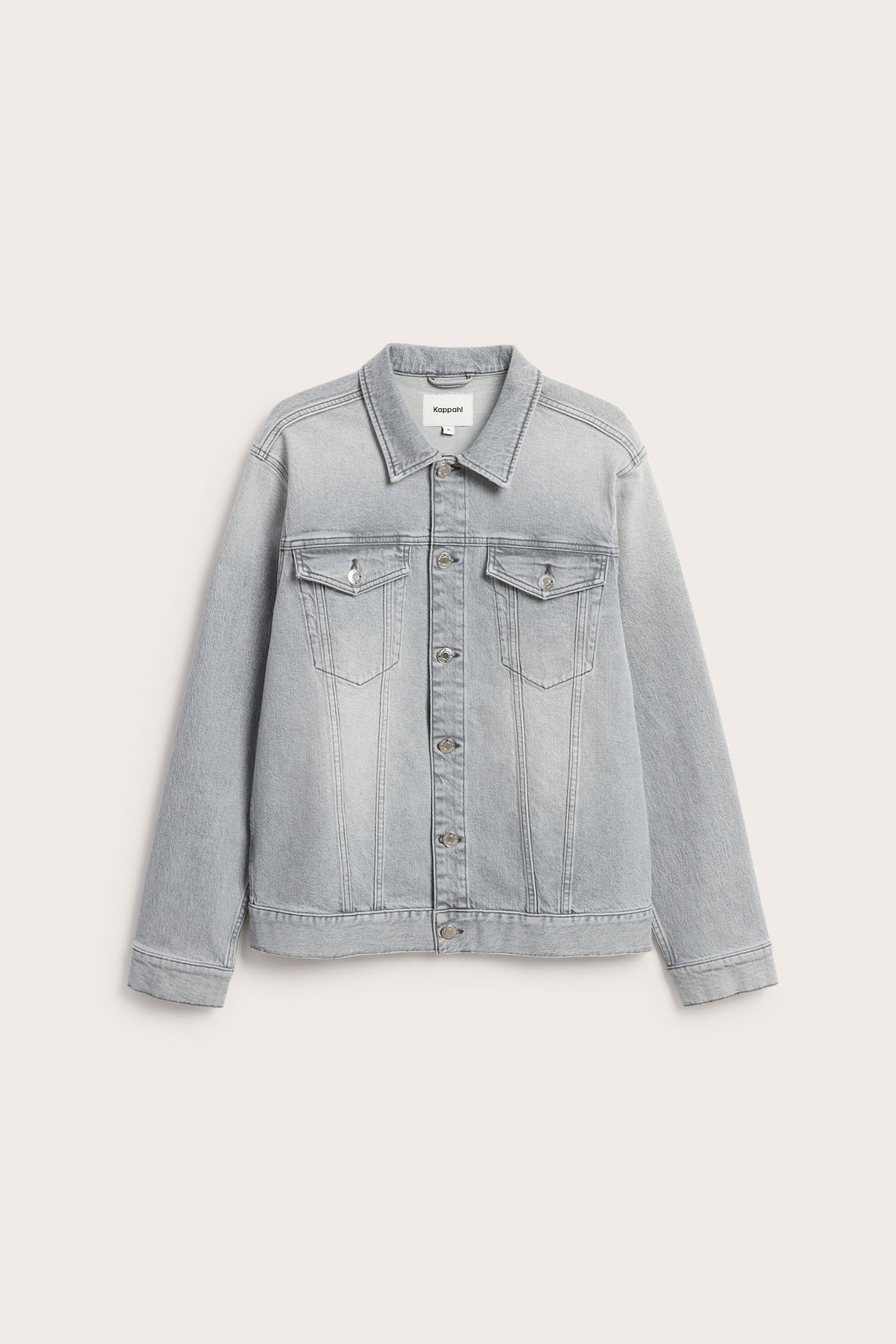 Forfra, en klassisk lys grå dongerijakke med metallknapper og to brystlommer.