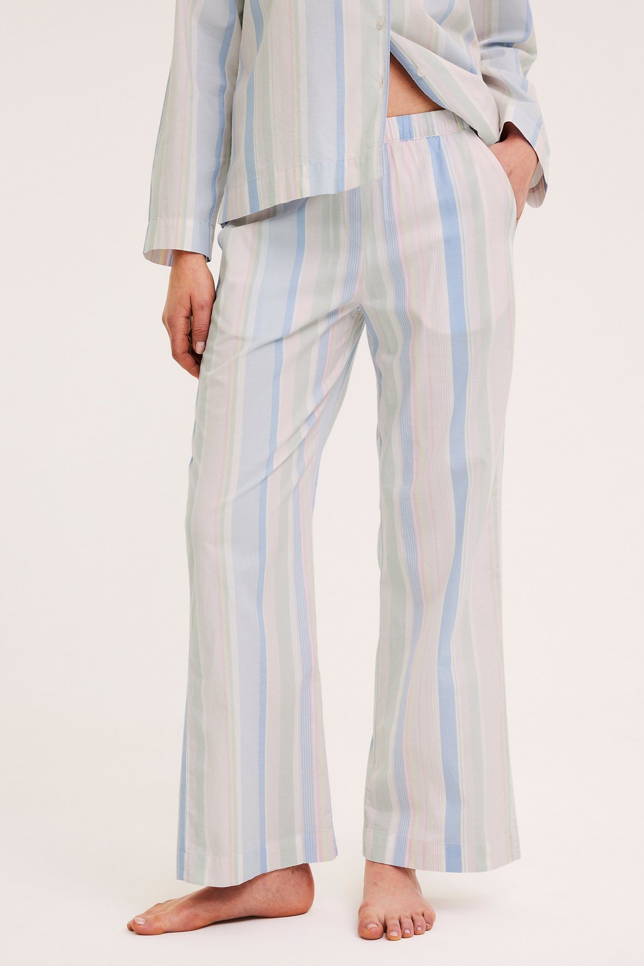 Forfra: kvinne i stripete pyjamasbukser av bomull med elastisk midje og matchende topp.