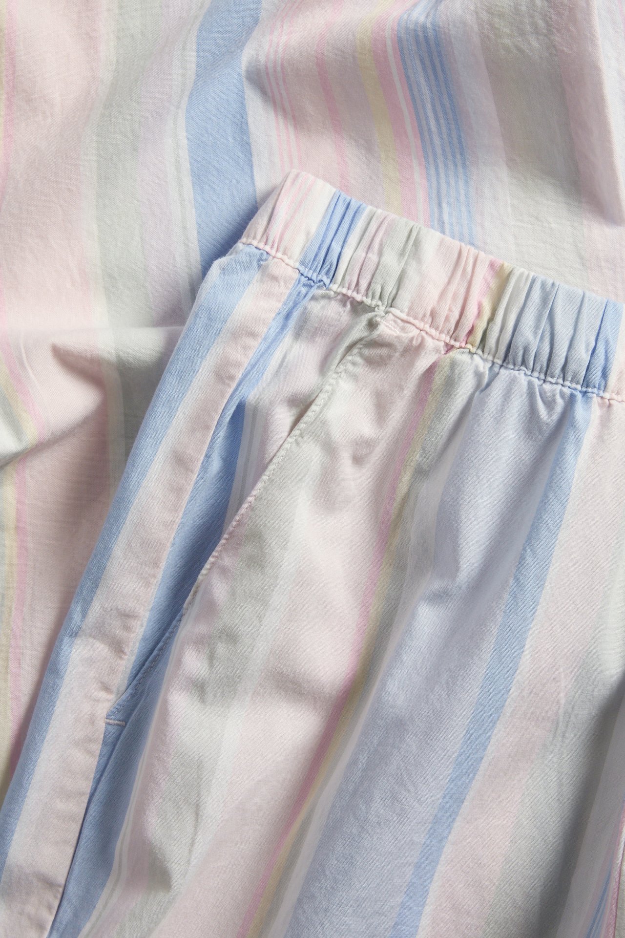 Nærbilde av pastellstripete pyjamasbukser i vevd bomull med elastisk linning og sidelommer.