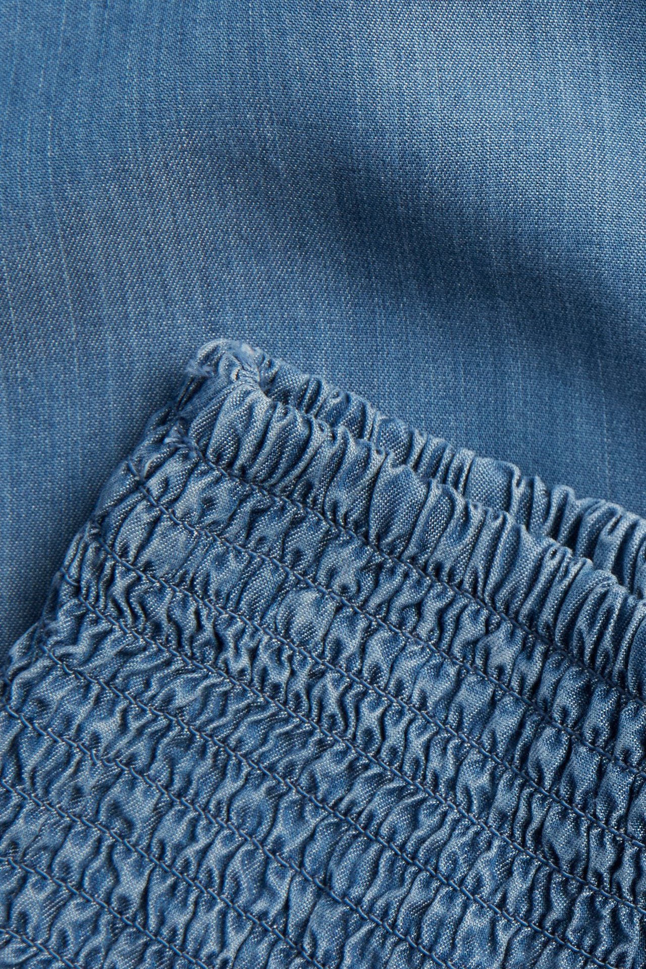 Närbild av blå Tencel-shorts med smockad midja.