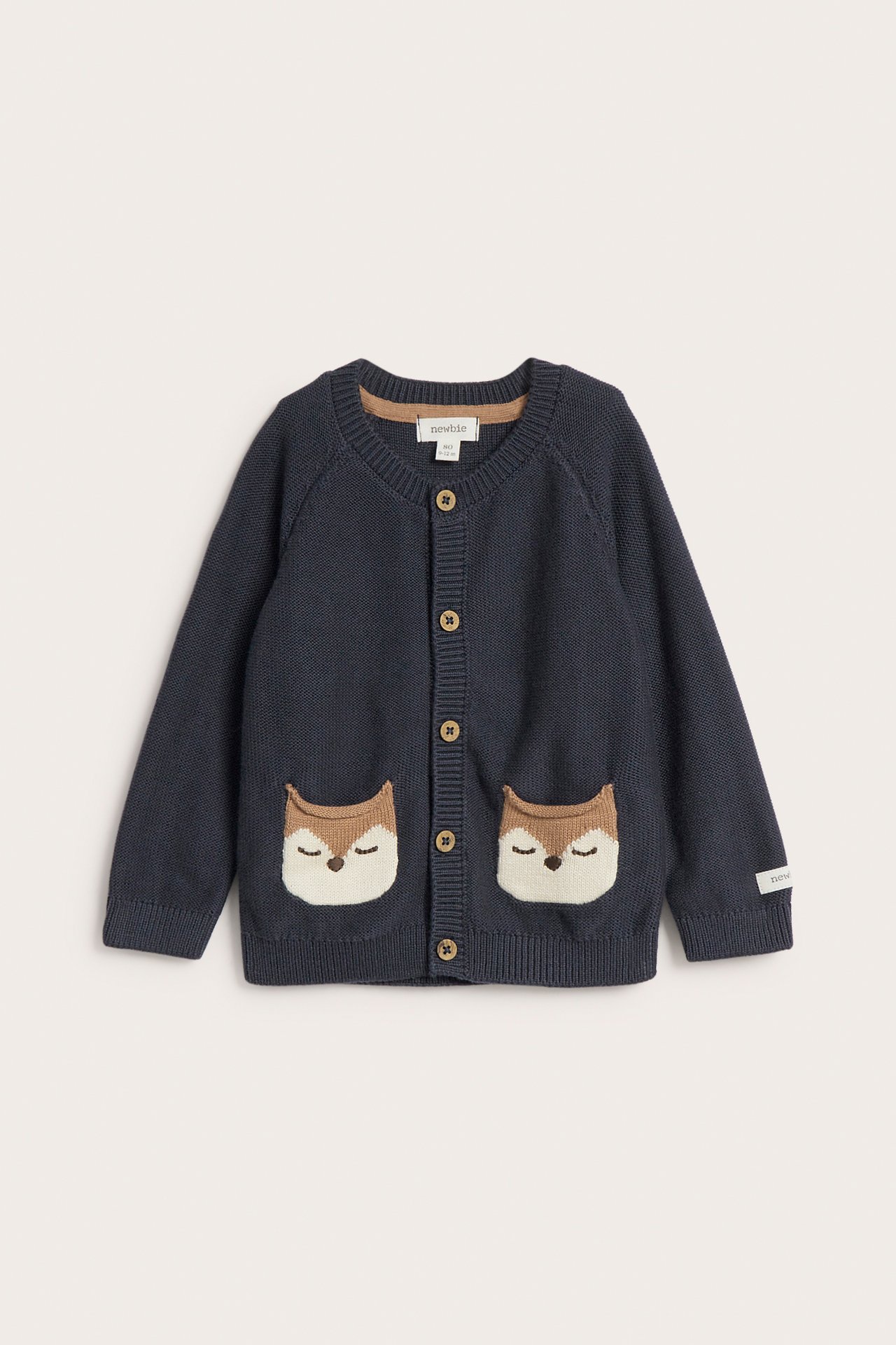Frontal visning av mørkeblå strikket babycardigan med sovende dyrefjeslommer og treknapper.