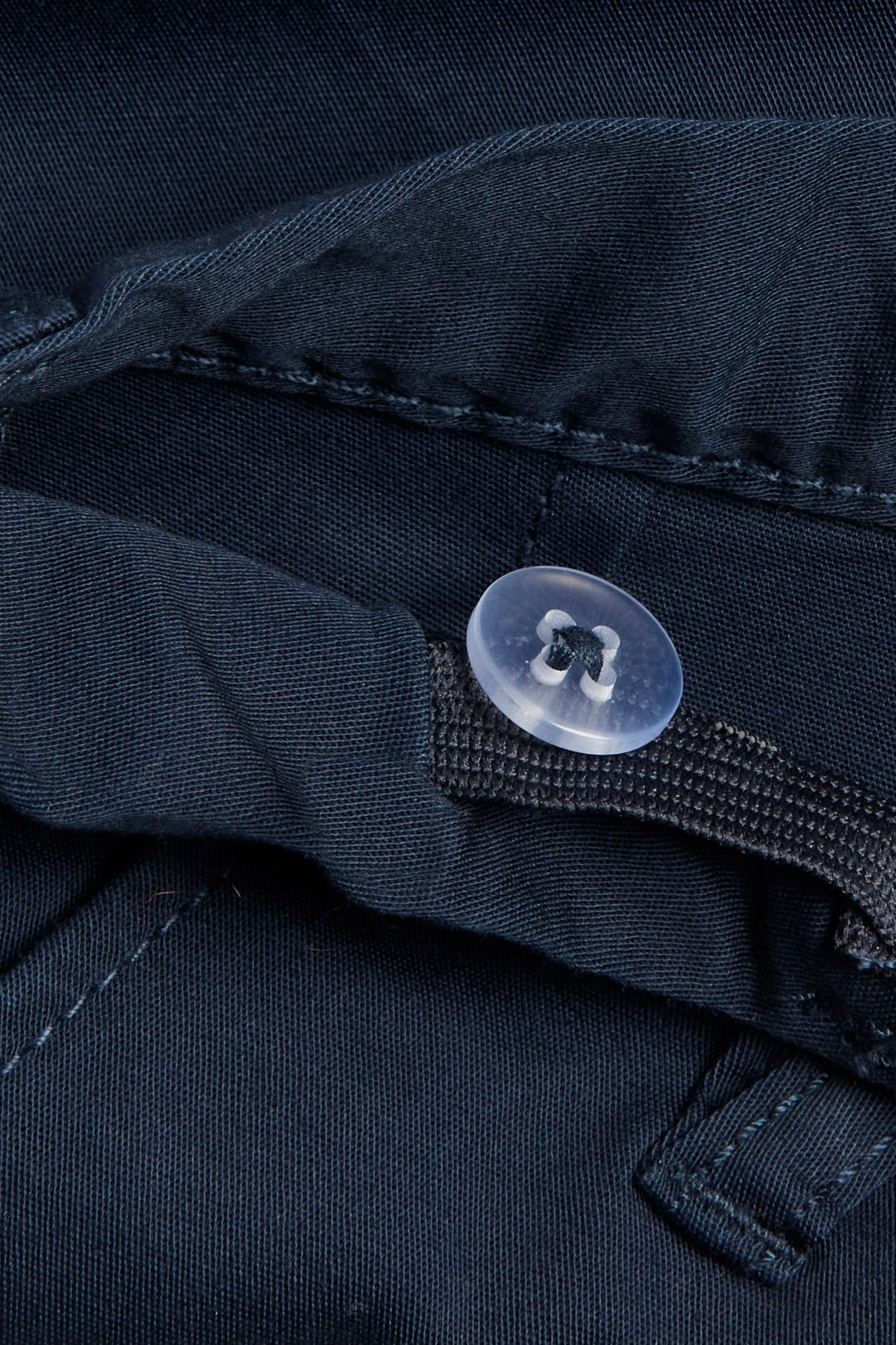 Zbliżenie na granatowe, bawełniane szorty chino dziecięce ze stretchem, przezroczystym guzikiem i regulacją w pasie.