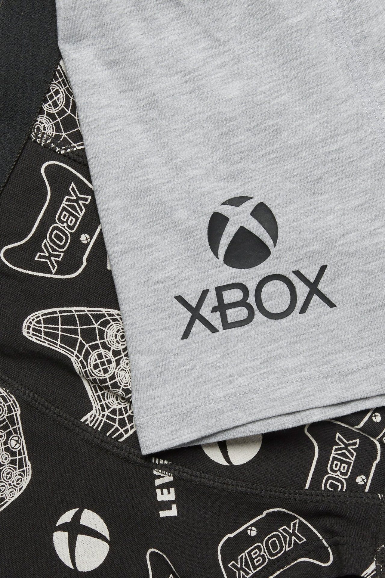 Zbliżenie na dwupak bokserek Xbox dla dzieci: jedne jasnoszare z logo, drugie czarne we wzory.