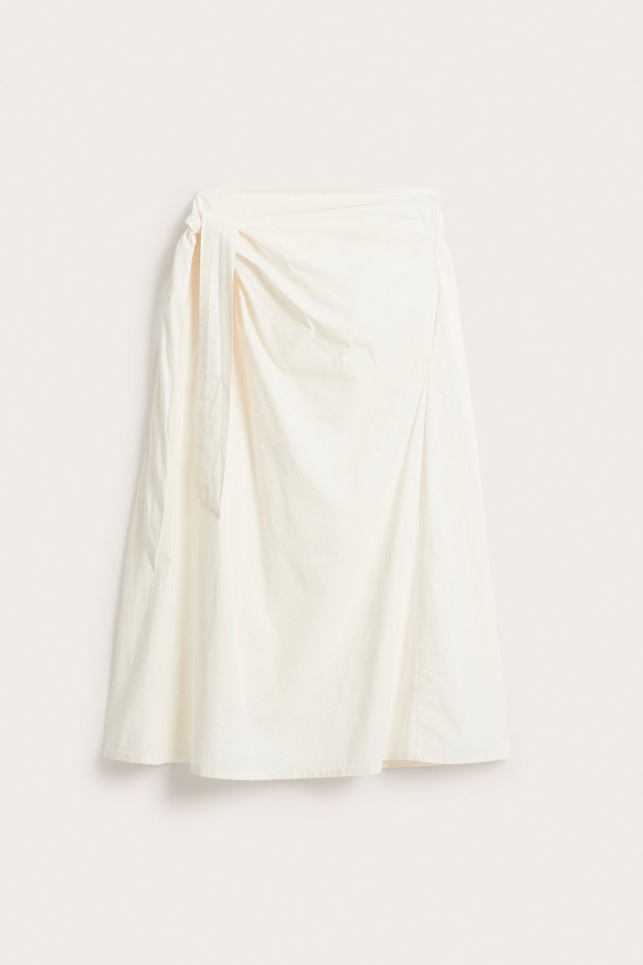 Edestäpäin valkoinen popliini-kietaimihame, jossa sivusidonta ja A-linjainen malli.