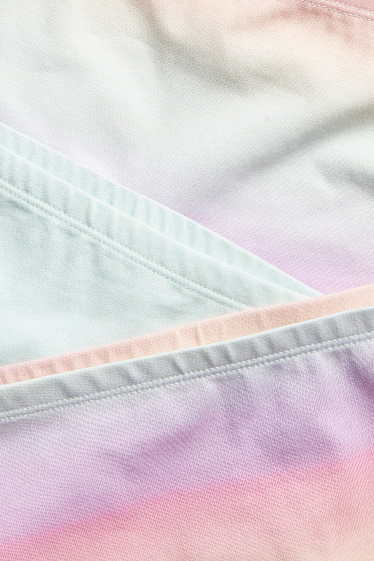 Nærbilde av tre mønstrede boksertruser: lys mintgrønn, blekrosa og en lilla-til-rosa gradient.