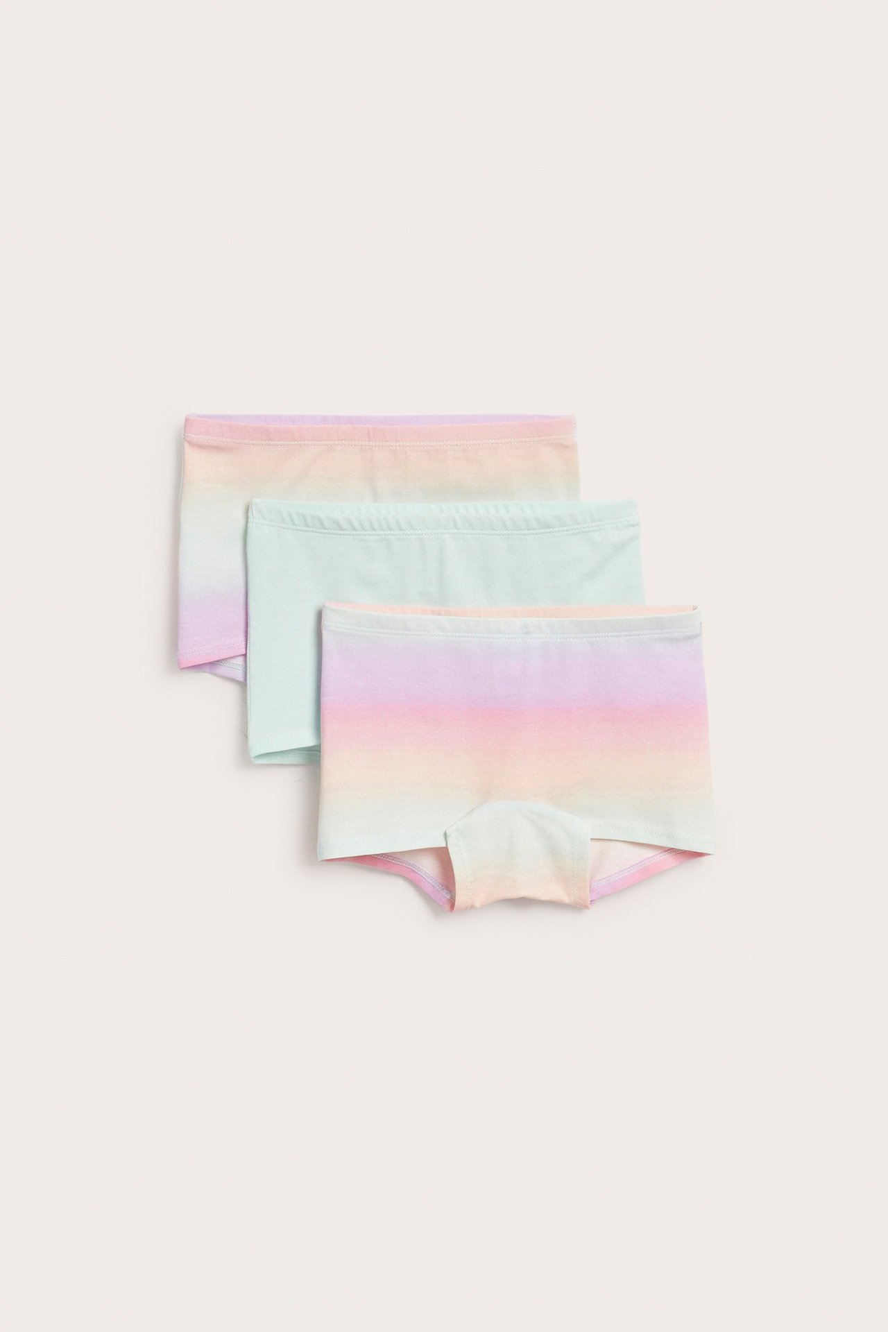 Kolme lasten bokserishortsia: yksi vaalean mintunvihreä ja kaksi sateenkaaren gradienttikuviolla.