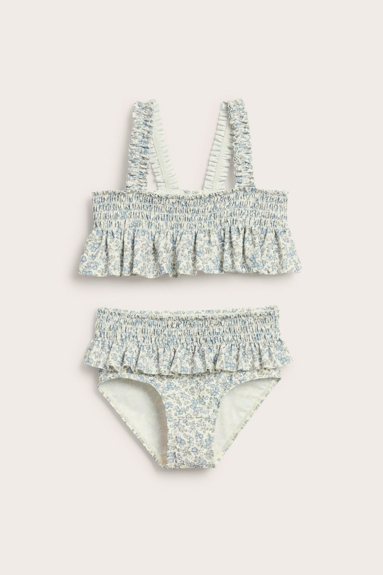 Widok z przodu: dziecięce bikini, marszczona góra i figi w jasnoniebiesko-zielony kwiatowy wzór, falbanki na ramiączkach.