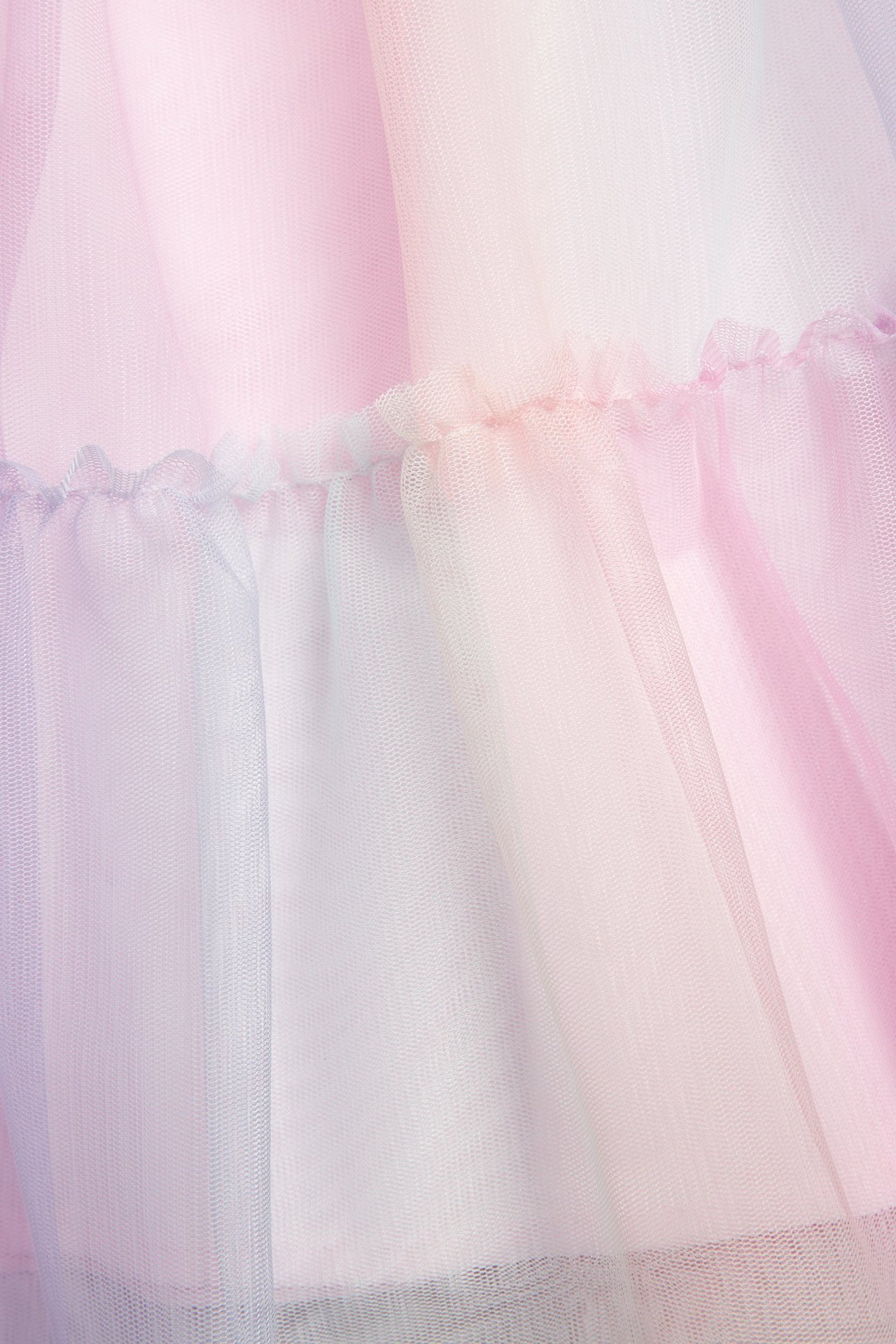 Lähikuva sateenkaarenvärisestä tyllimekon kankaasta, jossa on rypytettyjä yksityiskohtia.