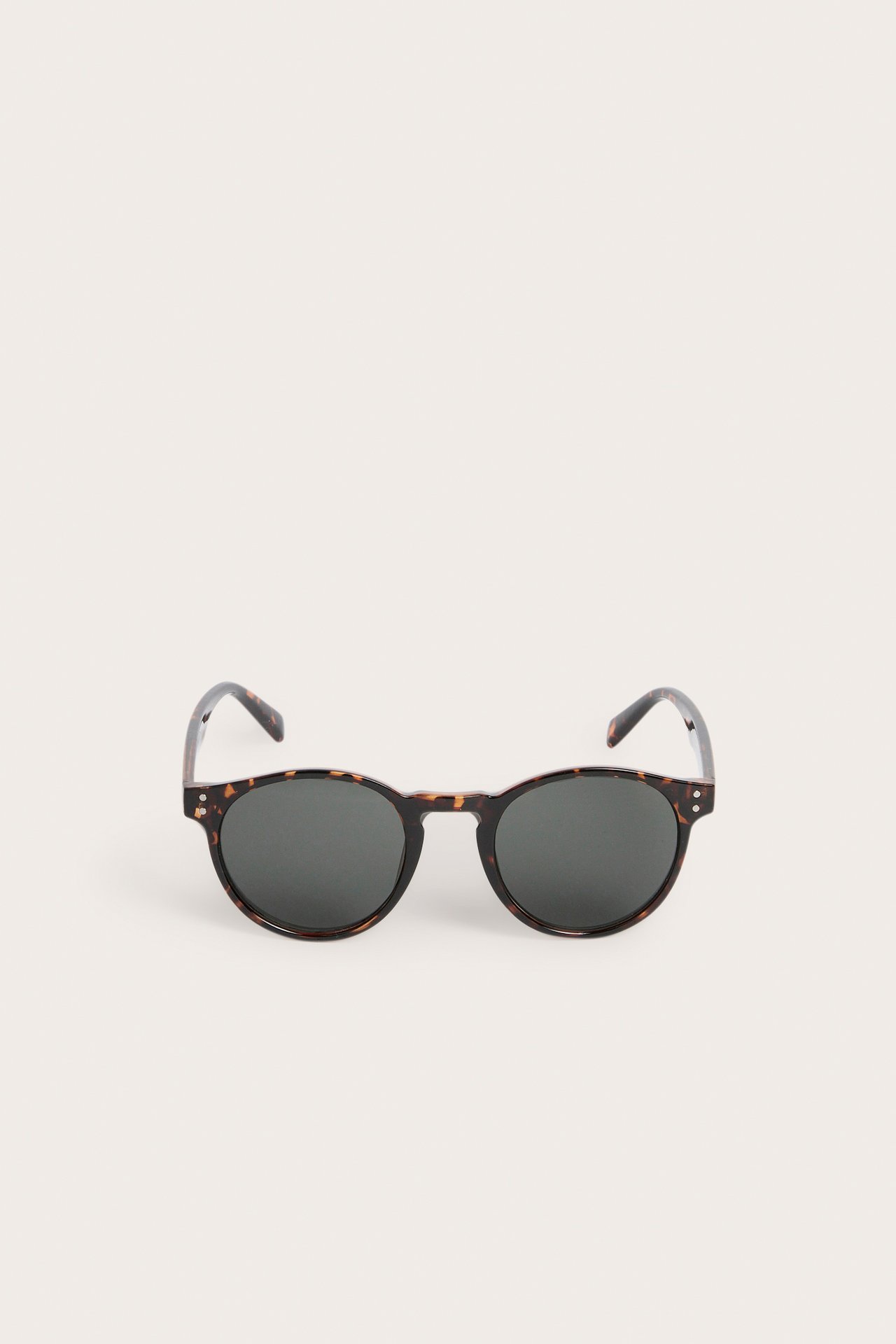 Edestäpäin, pyöreät kilpikonna-kuvioiset muoviset aurinkolasit tummilla linsseillä.