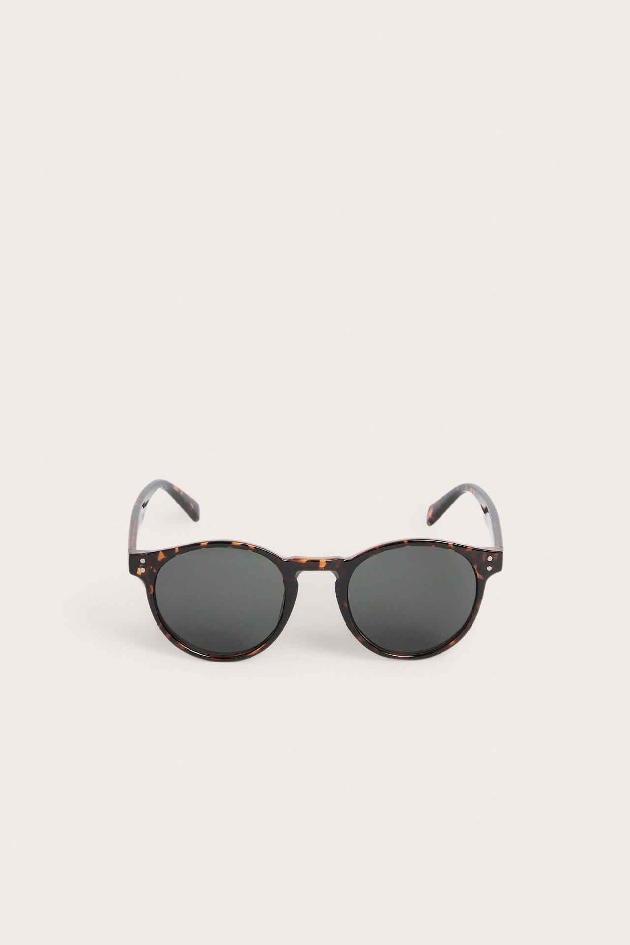 Edestäpäin, pyöreät kilpikonna-kuvioiset muoviset aurinkolasit tummilla linsseillä.