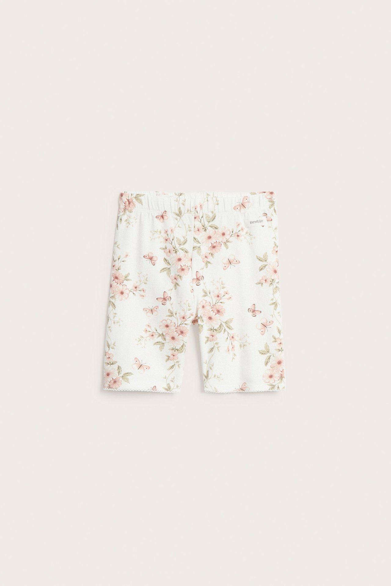 Widok z przodu ecru dżersejowych szortów kolarskich z kwiatowym i motylkowym wzorem, elastyczną talią i wykończeniem pikot.