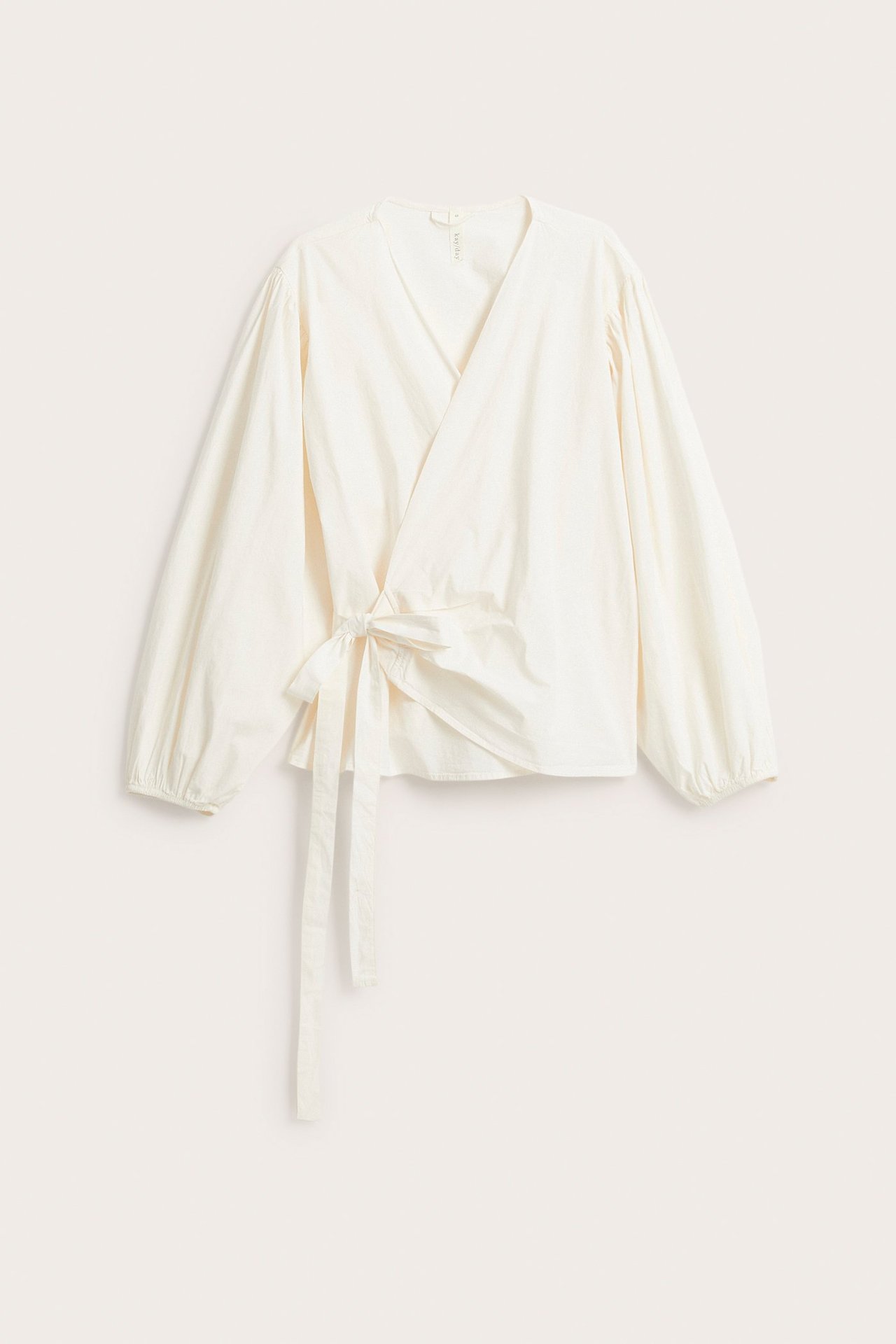 Edestä näkymä valkoisesta kietaisubluzista, jossa on leveät pussihihat ja sidottava vyö sivulla.