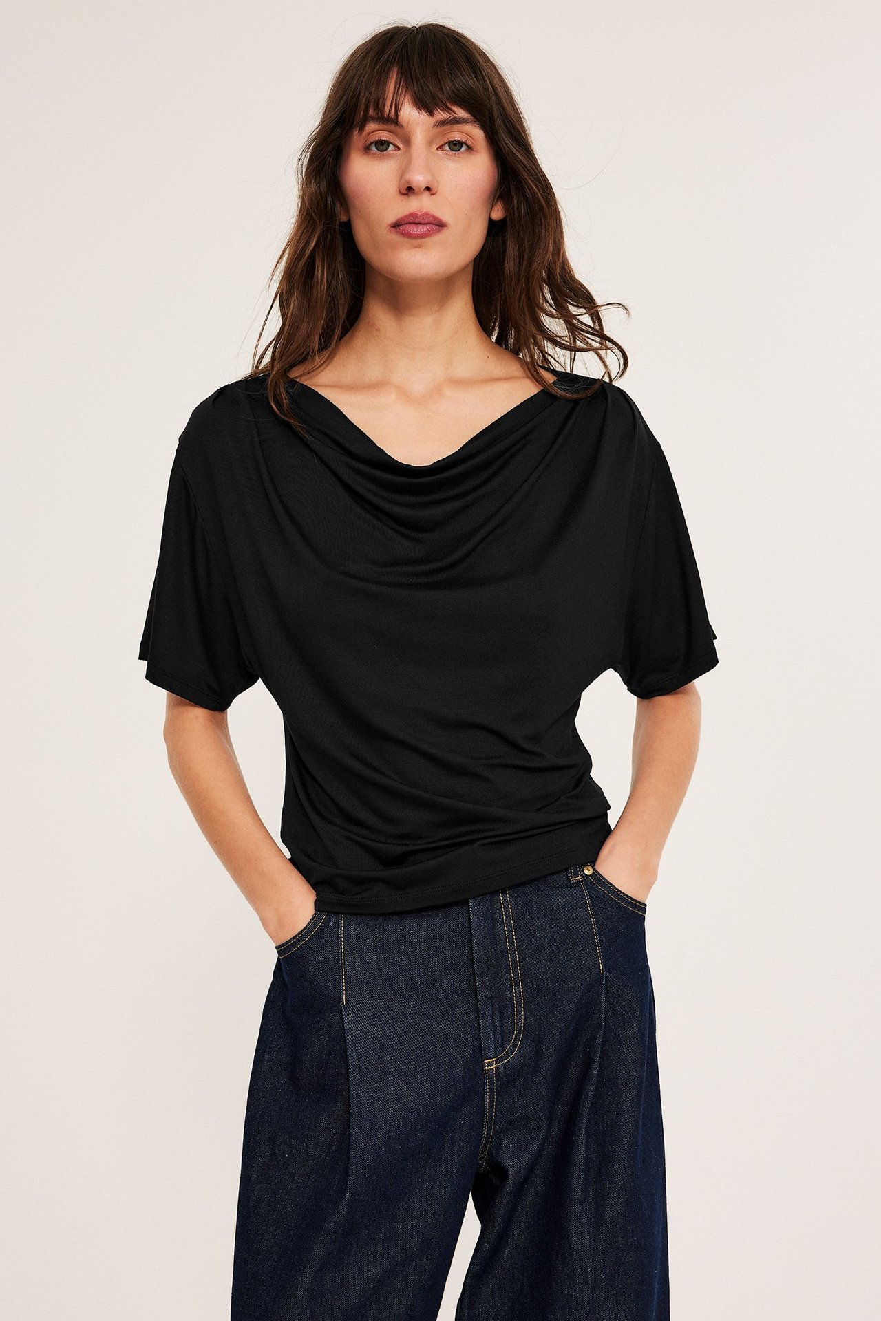 Czarna krótki rękaw top z viskozy z draperią, na ciemnych spodniach, przód.