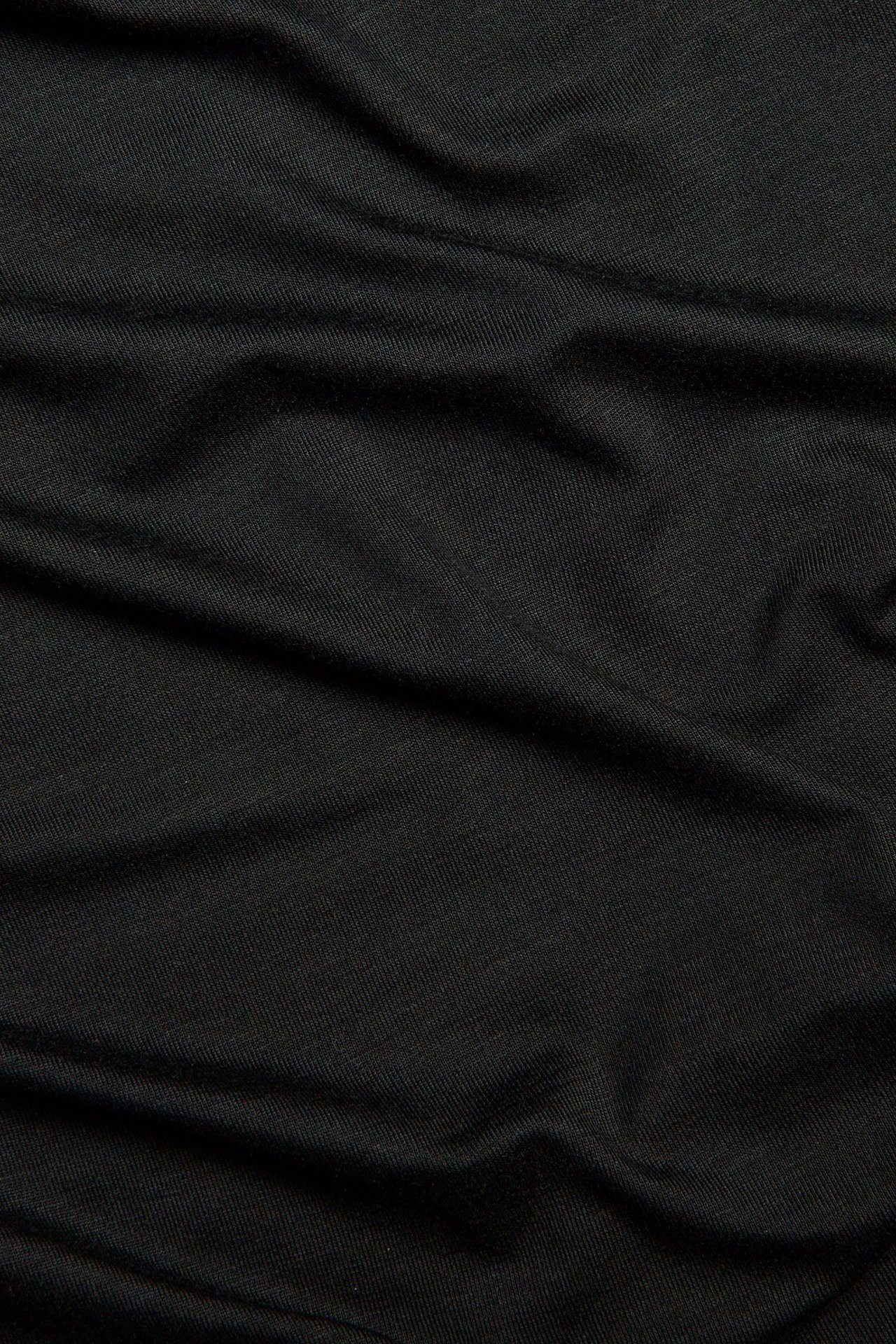 Zbliżenie czarnej, jednolitej tkaniny z mieszanki wiskozy z miękkim udrapowaniem i fałdami.