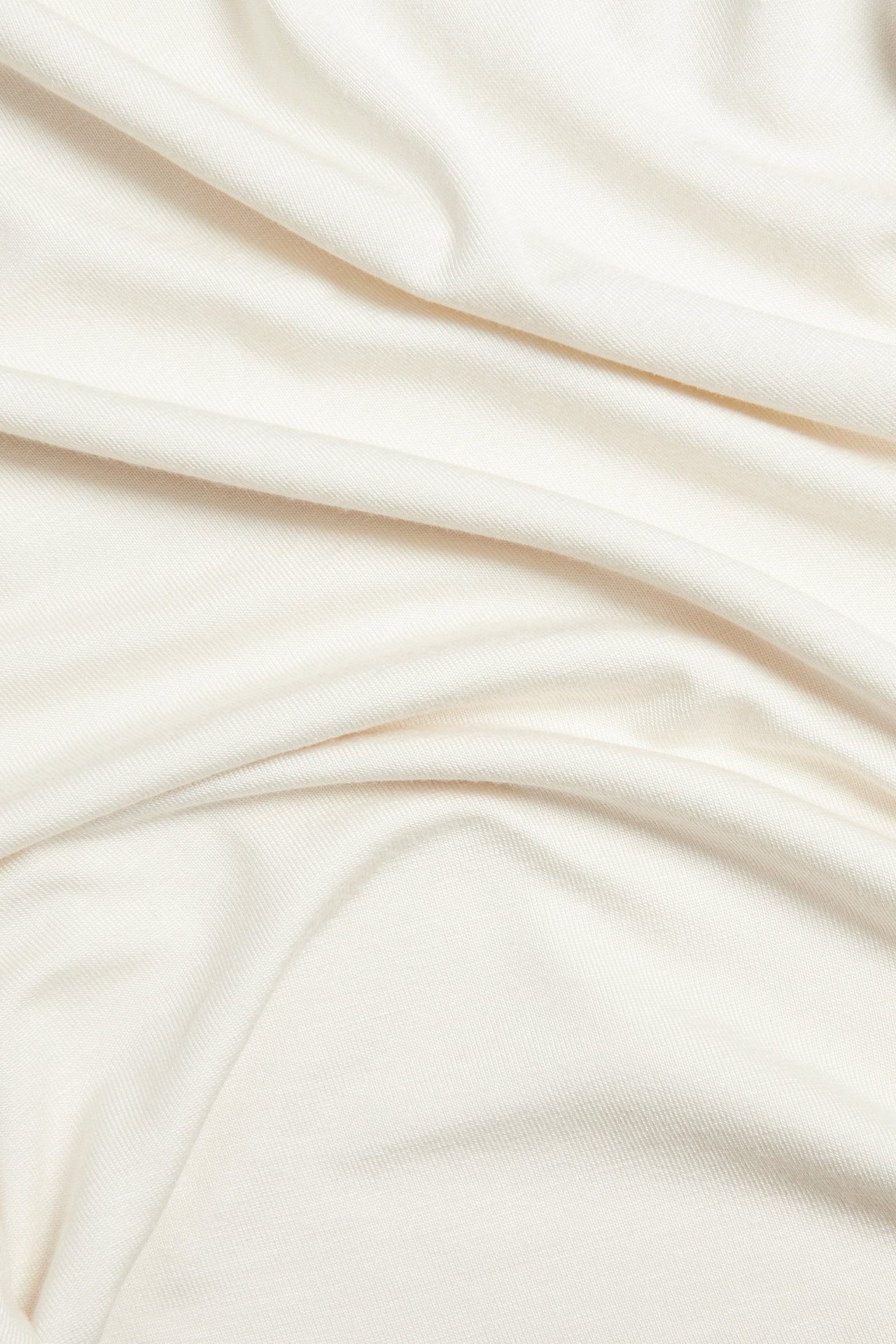 Zbliżenie na gładką tkaninę wiskozową w kolorze ecru z miękkimi fałdami.