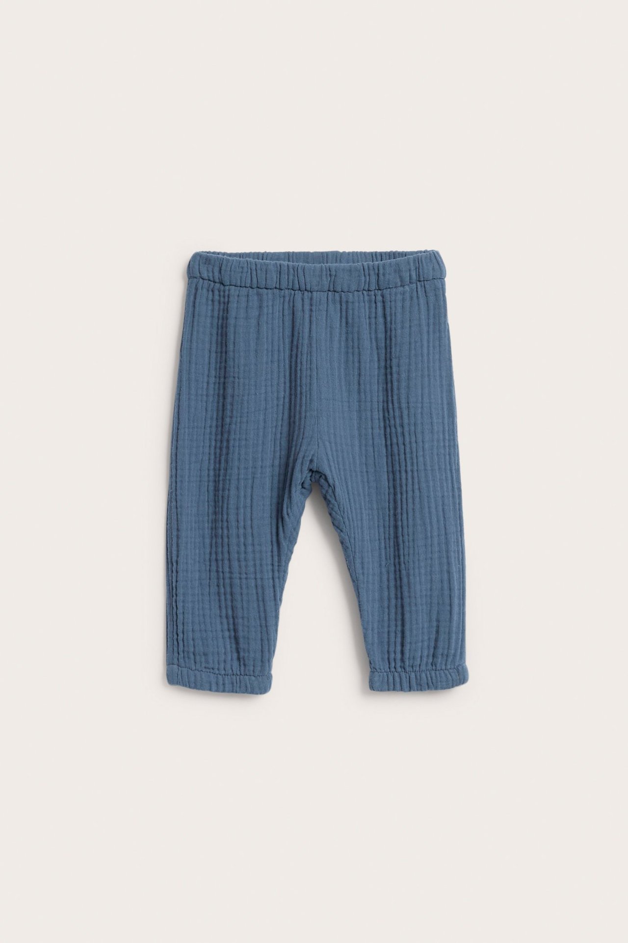 Frontbilde av ensfargede blå baby-muslinbukser med strikk i midjen og nederst på bena.