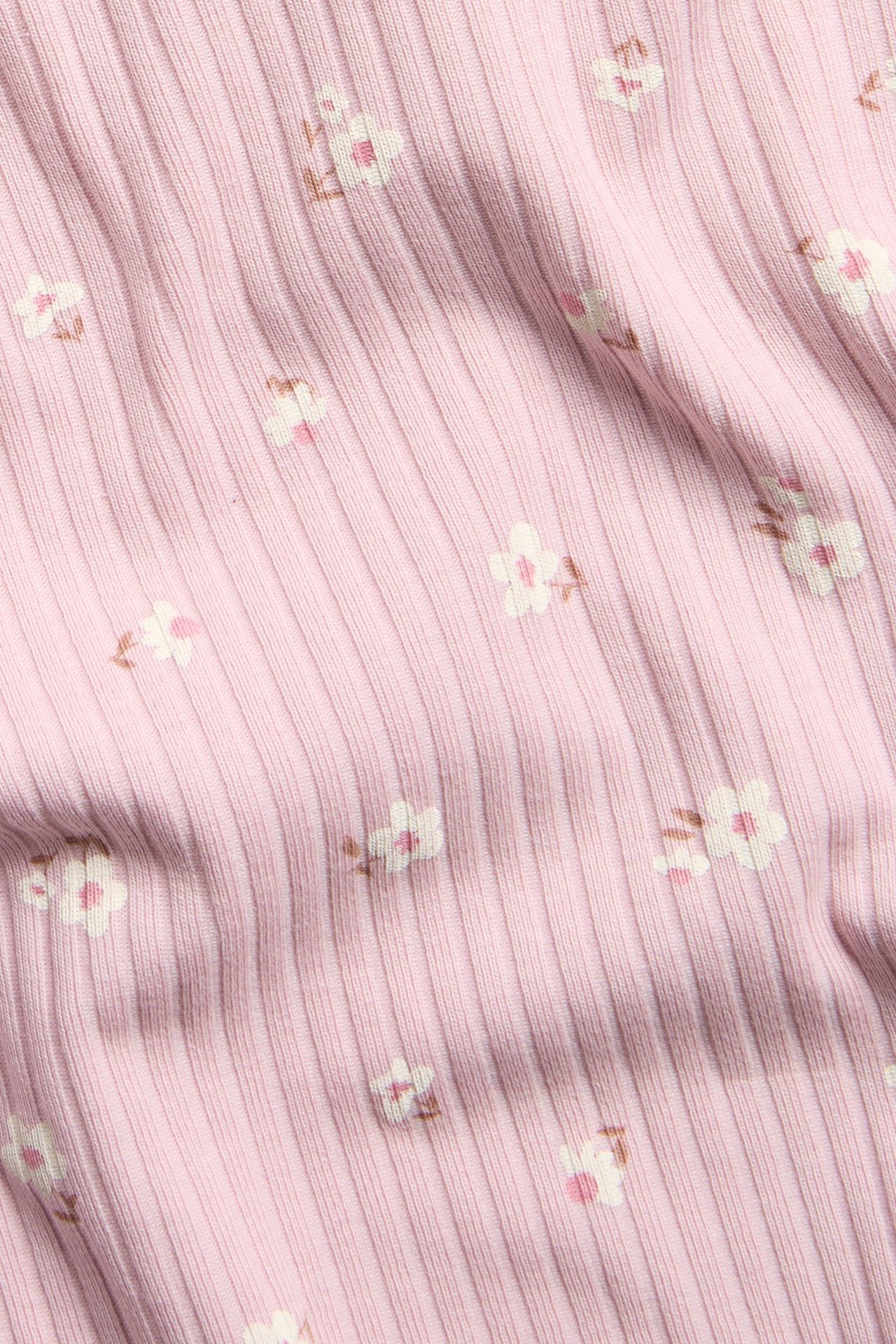 Lähikuva vaaleanpunaisesta ribatusta lyhythihaisesta topista kukkakuvioinnilla.