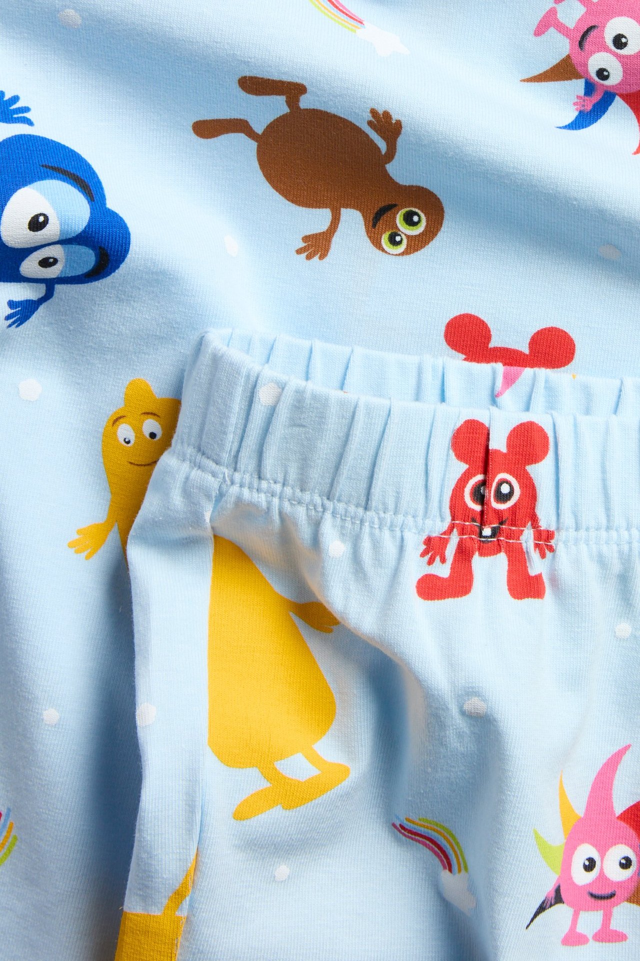 Närbild på ett ljusblått pyjamasset i bomull för barn, med färgglatt Babblarna-tryck och resårmidja.