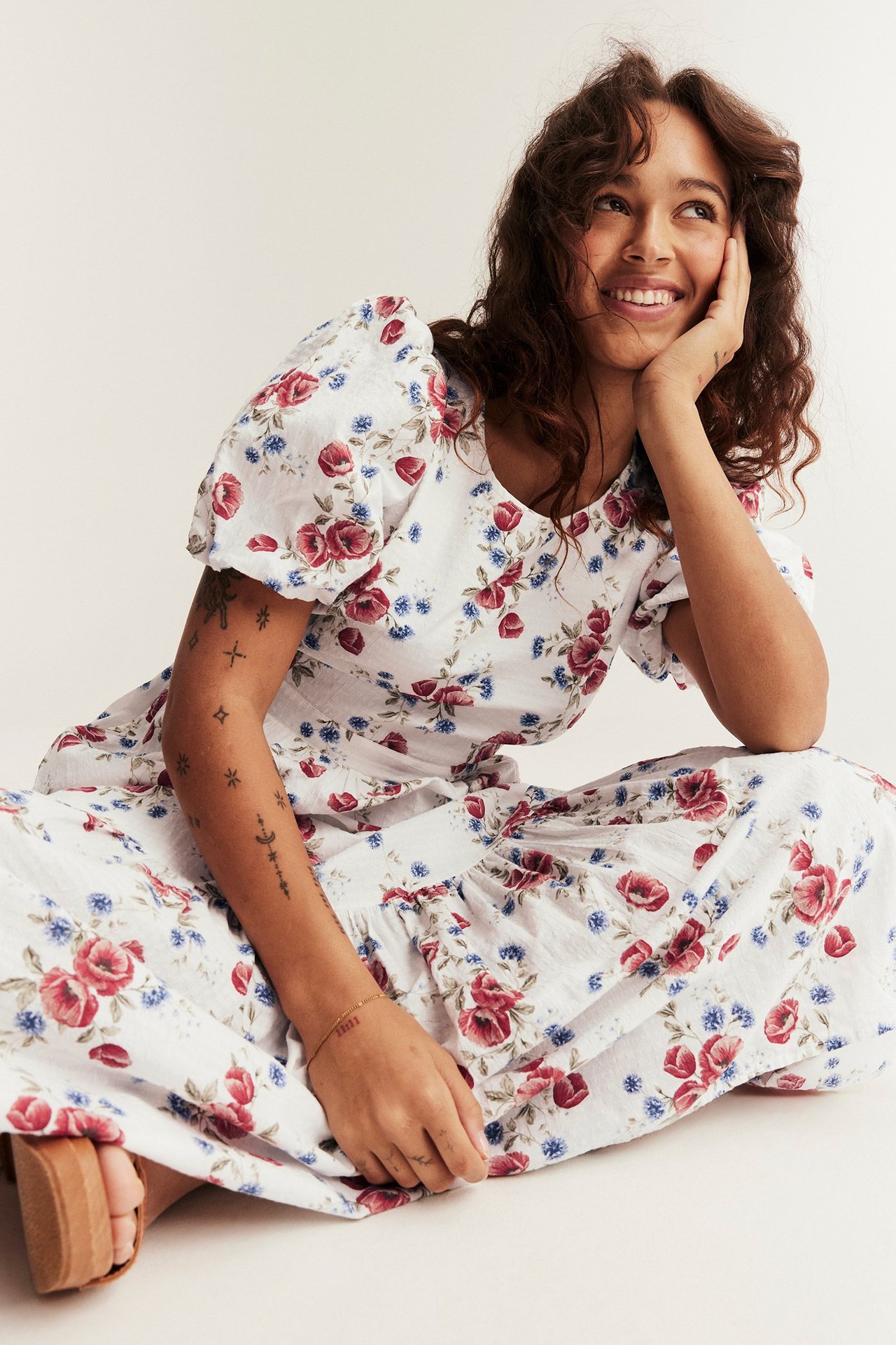 Forfra: Kvinne i en offwhite blomstret vevd kjole med ballongermer og brune platåsandaler.