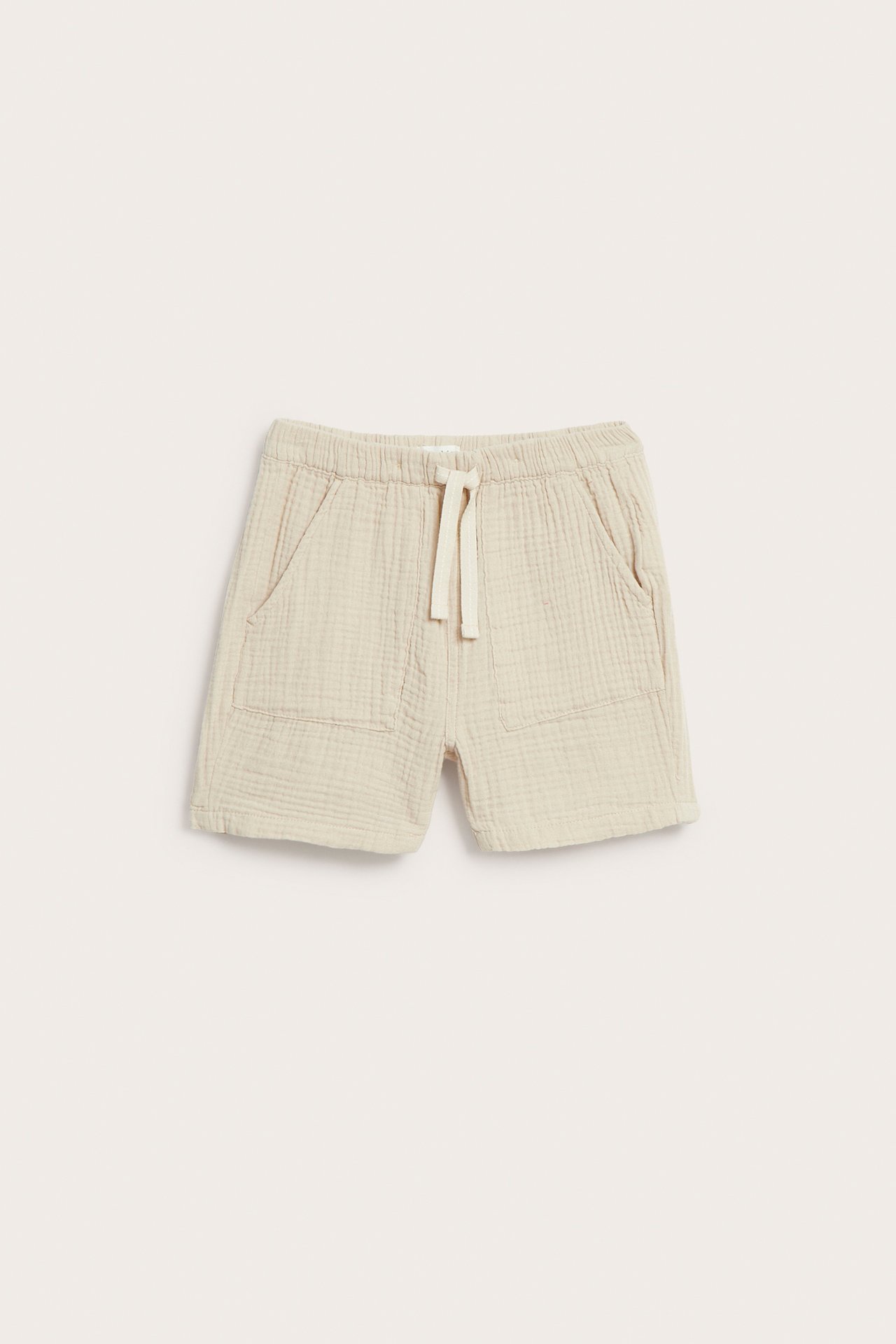Framifrån, offwhite vävda shorts med resårmidja med dragsko och påsydda fickor.