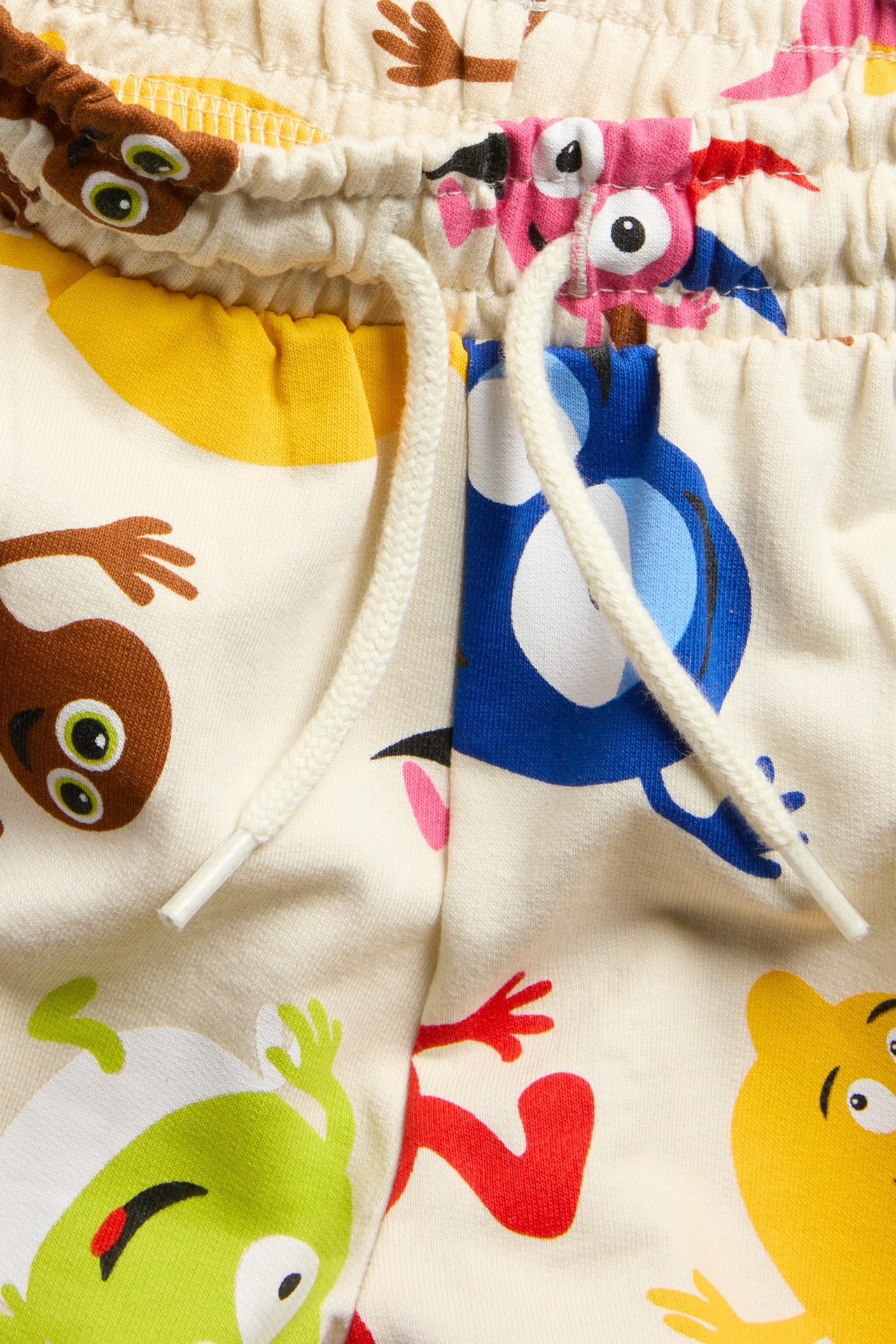 Närbild på ljusbeige bomullsshorts med färgglatt Babblarna-mönster och vit dragsko.