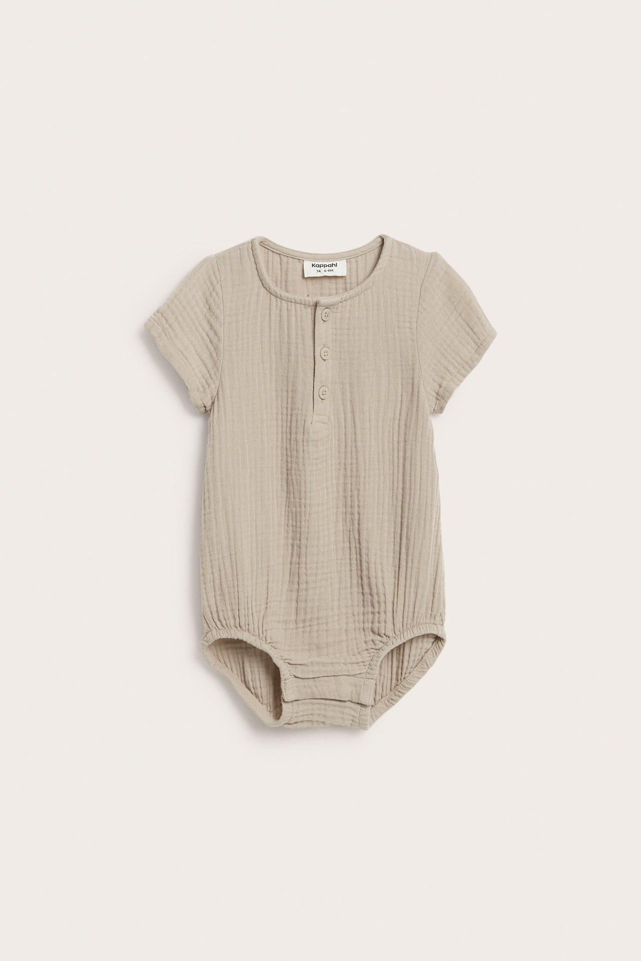 Frontvisning av en beige kortermet babybody i musselin med knapper foran og trykknapper.