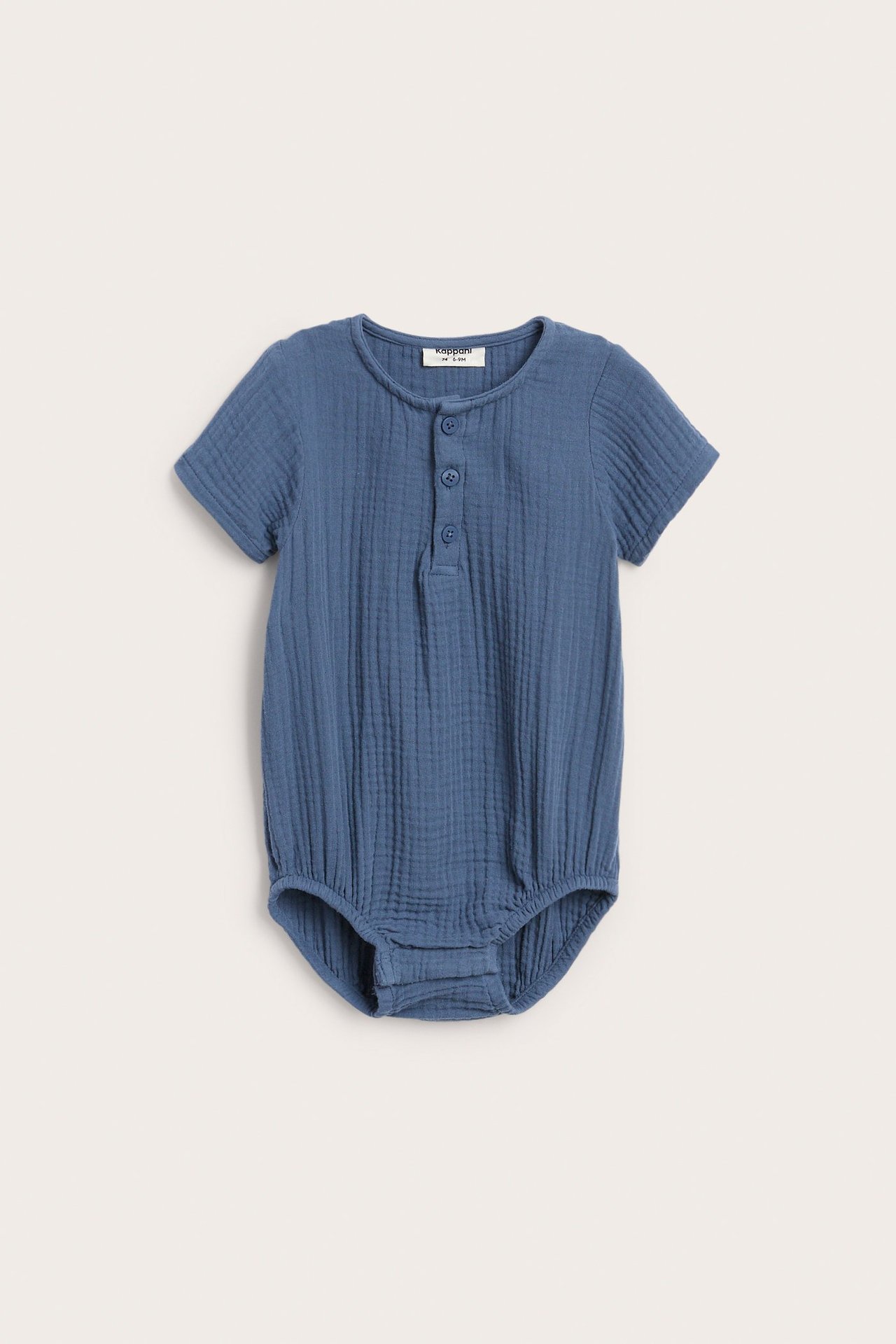 Edestä: sininen lyhythihainen musliinibody vauvalle, napit edessä ja nepparit haaroissa.