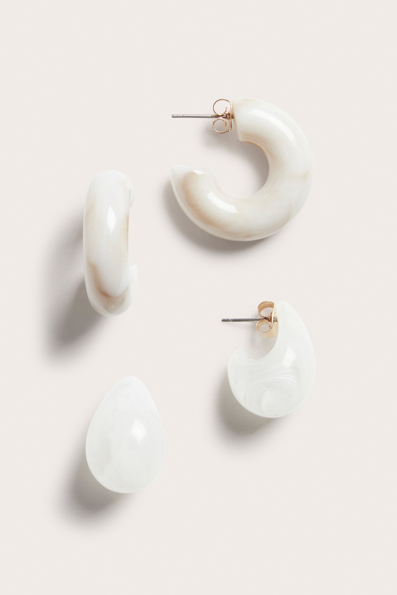 Ovenfra sett av en 2-pakning mønstrede lys beige plastøreringer: kraftige ringer og dråpeformede ørepropper.