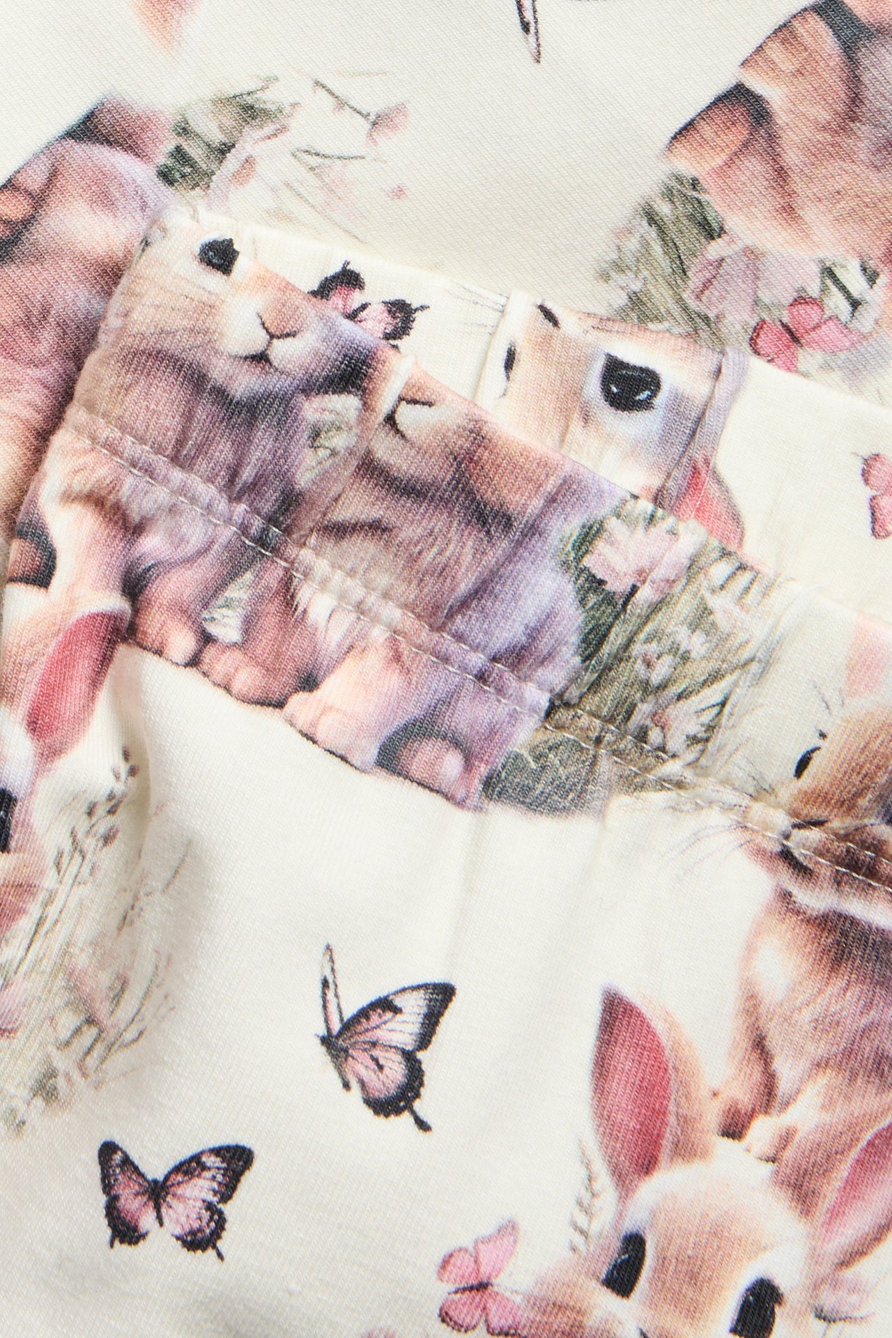 Nærbilde av offwhite bomullsjersey leggings med elastisk linning og heldekkende kaninmønster.