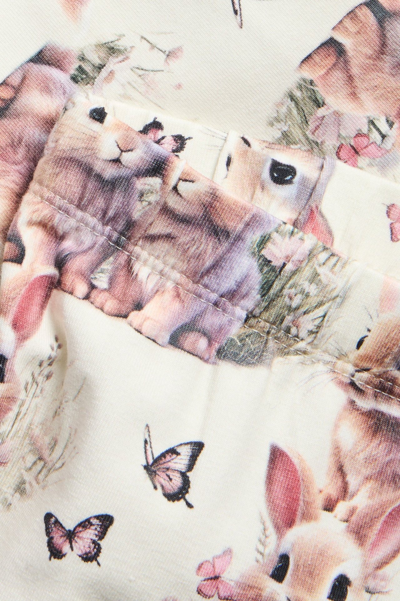 Zbliżenie legginsów z off-white bawełny dżersejowej z elastycznym pasem i nadrukiem królików.